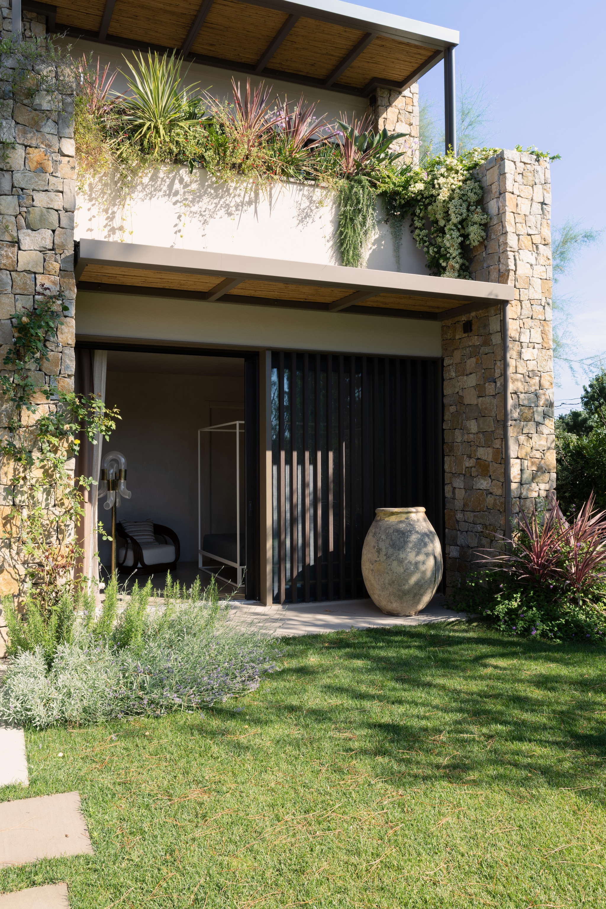 Detail van de buitelgevel met geïntegreerde plantenbakken. Vintage Franse kruik. vtwonen Design 02-2026 | fotografie Monica Spezia | productie Living Inside