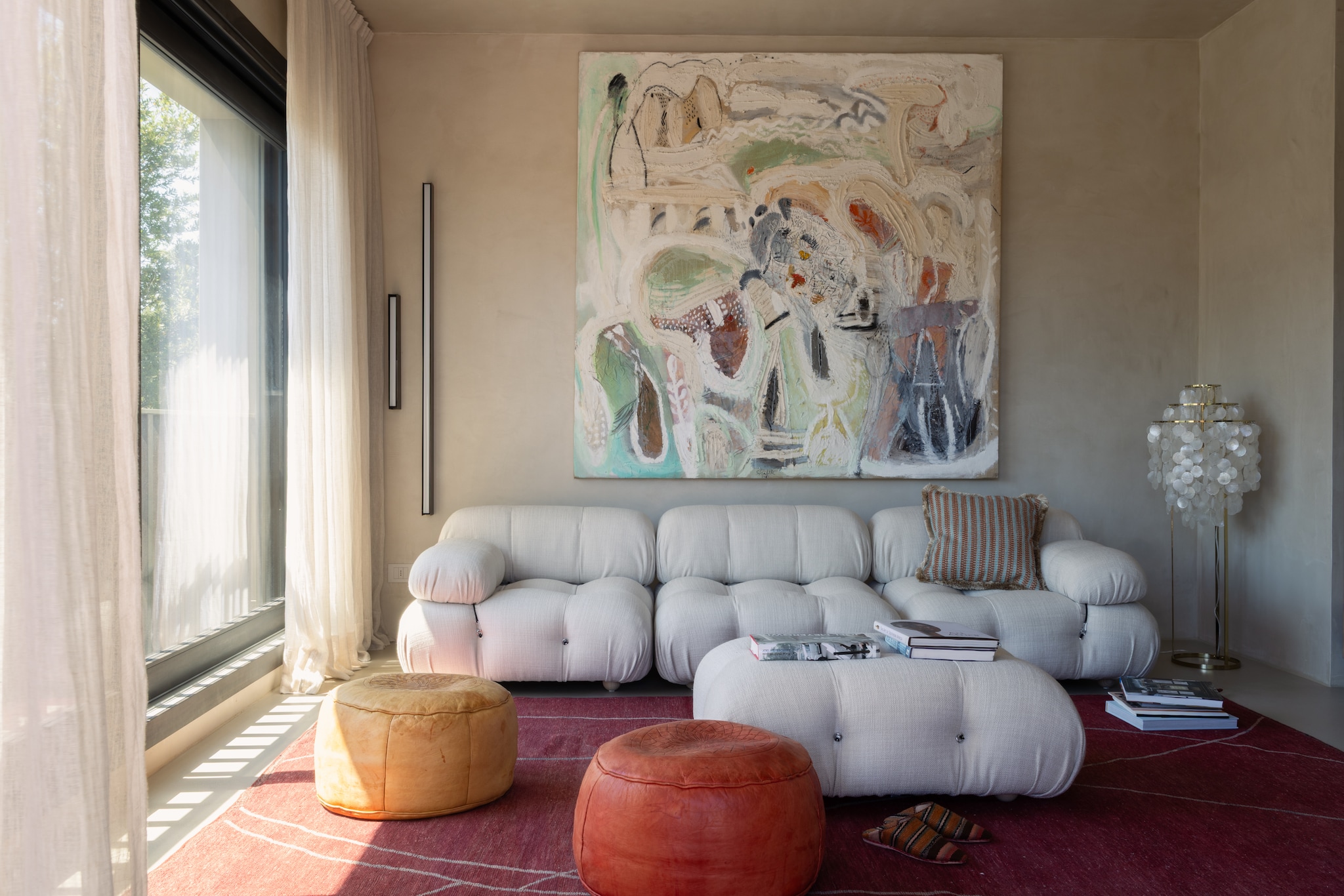 Bank Camaleonda van B&b Italia. Kussen Manifattura Forasassi. Schilderij Medhat Shafik. Wandlapen Ubrass van Vesoi. Vintage Marokkaanse poefs. Marokkaans tapijt Soufiane Zarib. Gordijnen van linnen gaasstof. vtwonen Design 02-2026 | fotografie Monica Spezia | productie Living Inside