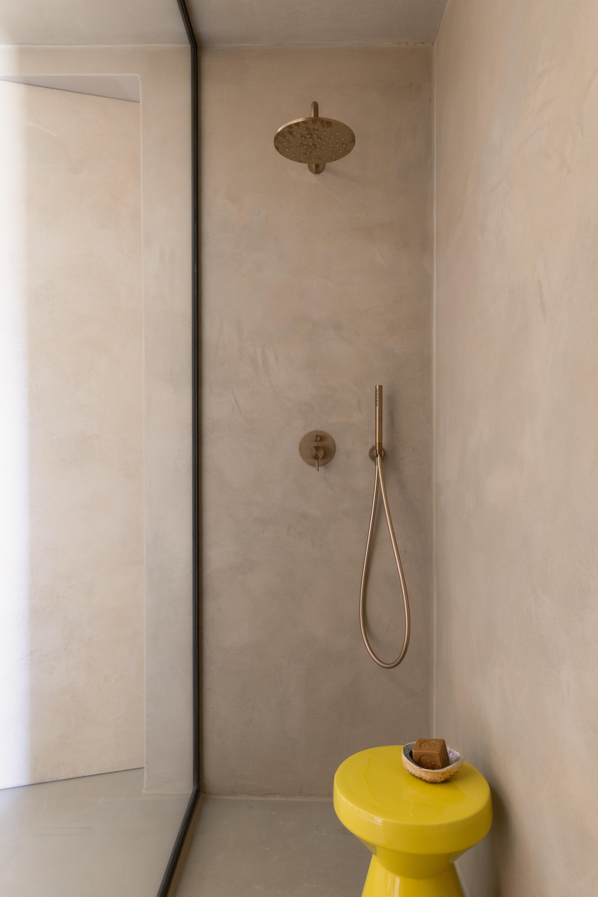 De douche met wanden afgewerkt in kalkpleister. Bijzettafel La Redoute. vtwonen Design 02-2026 | fotografie Monica Spezia | productie Living Inside