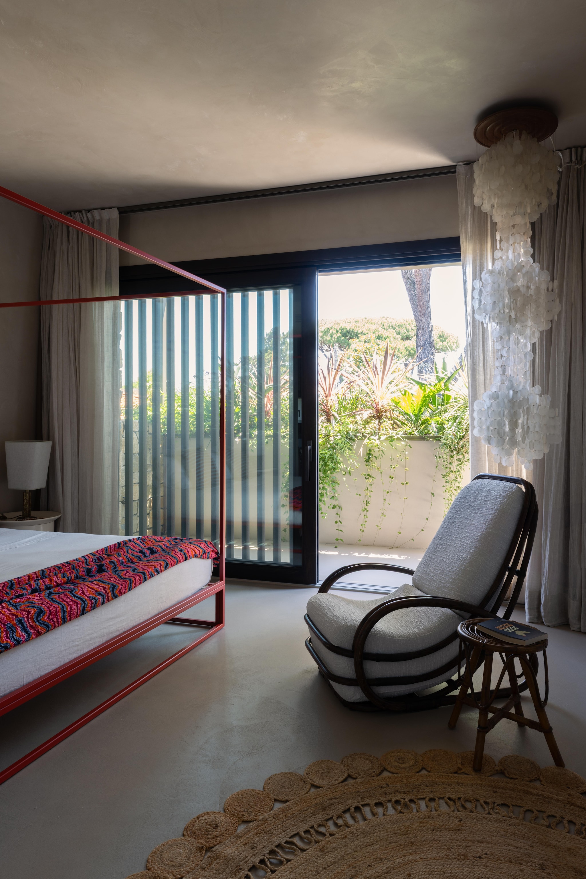 Metalen hemelbed Xam. Sprei van Afrikaanse stof. bamboestoel en bijzettafel vintage. Parelmoeren hanglamp Pamono. Soortgelijk vloerkleed Mrcarpet. vtwonen Design 02-2026 | Fotografie Monica Spezia | Productie Living Inside