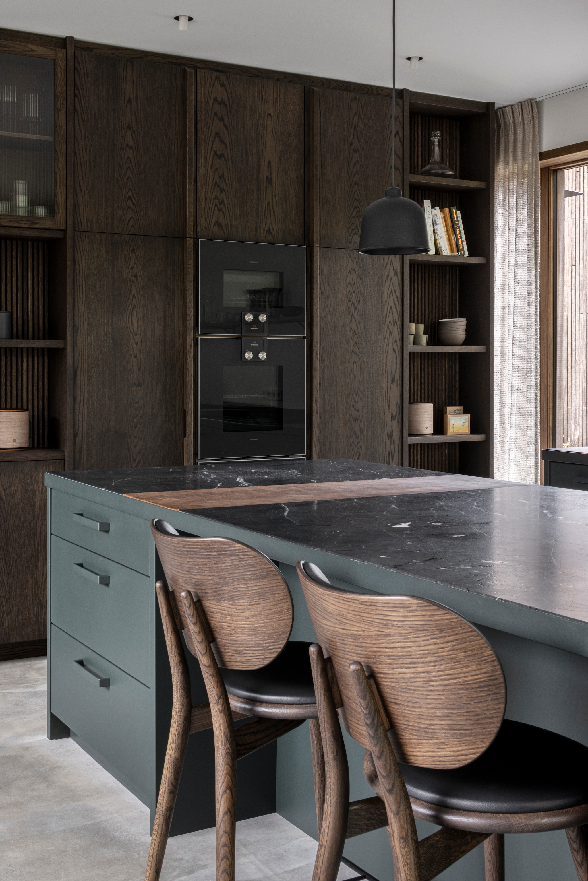 Keukenstoelen Mater Design High Stool Backrest 69. Hanglamp Muuto. De vloer is gemaakt van gevlinderd cement, de traptreden van Grigio Alpi-kalksteen. vtwonen Design 02-2026 | fotografie Tim Van de Velde