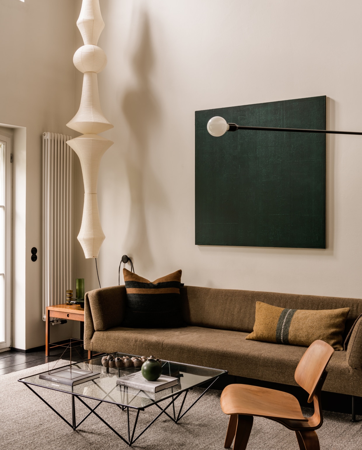 Lichtsculptuur Akari E van Isamu Noguchi voor Vitra. Vintage teakhouten bijzettafel. Loungestoel Lcw van Ray en Charles Eames voor Herman Miller. Schilderij Color Square van Piotr Kuchciński. Bank Muse van Piotr Kuchciński voor Noti. Kussens Libeco. Sculptuur Anne Rose Regenboog. stijlvol wonen 10-2025 | fotografie oni studio