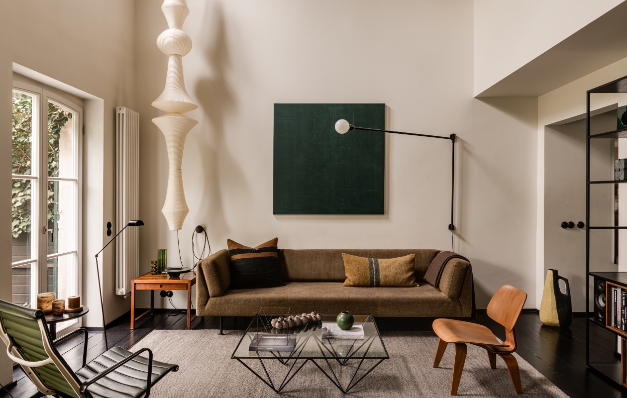 Vintage teakhouten bijzettafel. Loungestoel Lcx en fauteuil Ea124 van Ray en Charles Eames voor Herman Miller. Grote vaas rechts vintage. Muurlamp Potence Pivotante van Charlotte Perriand voor Nemo. Rek Stepps van Piotr Kuchciński voor Balma. stijlvol wonen 10-2025 | fotografie oni studio