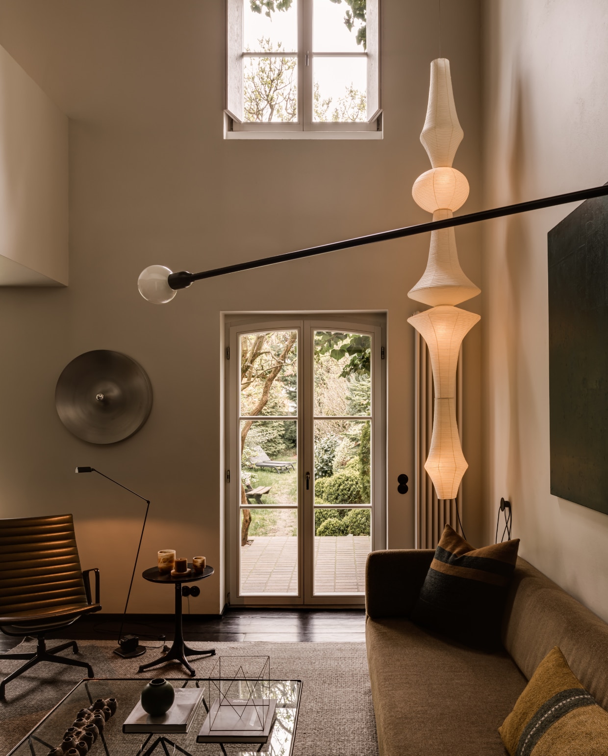 Lichtsculptuur Akari E van Isamu Noguchi voor Vitra. Op de voorgrond muurlamp Potence Pivotante van Charlotte Perriand voor Nemo. Vintage leeslamp Daphine van Tommaso Cimini voor Lumina. Vintage wandlamp van Charlotte Perriand voor Les Arcs. Vintage fauteuil Ea124 van Ray en Charles Eames voor Herman Miller. Bijzettafel Pedestal van George Nelson voor Herman Miller. Sofa Muse van Piotr Kuchciński voor Noti. Kussens Libeco. Sculptuur Anne Rose Regenboog. Schilderij Color Square van Piotr Kuchciński. stijlvol wonen 10-2025 | fotografie oni studio