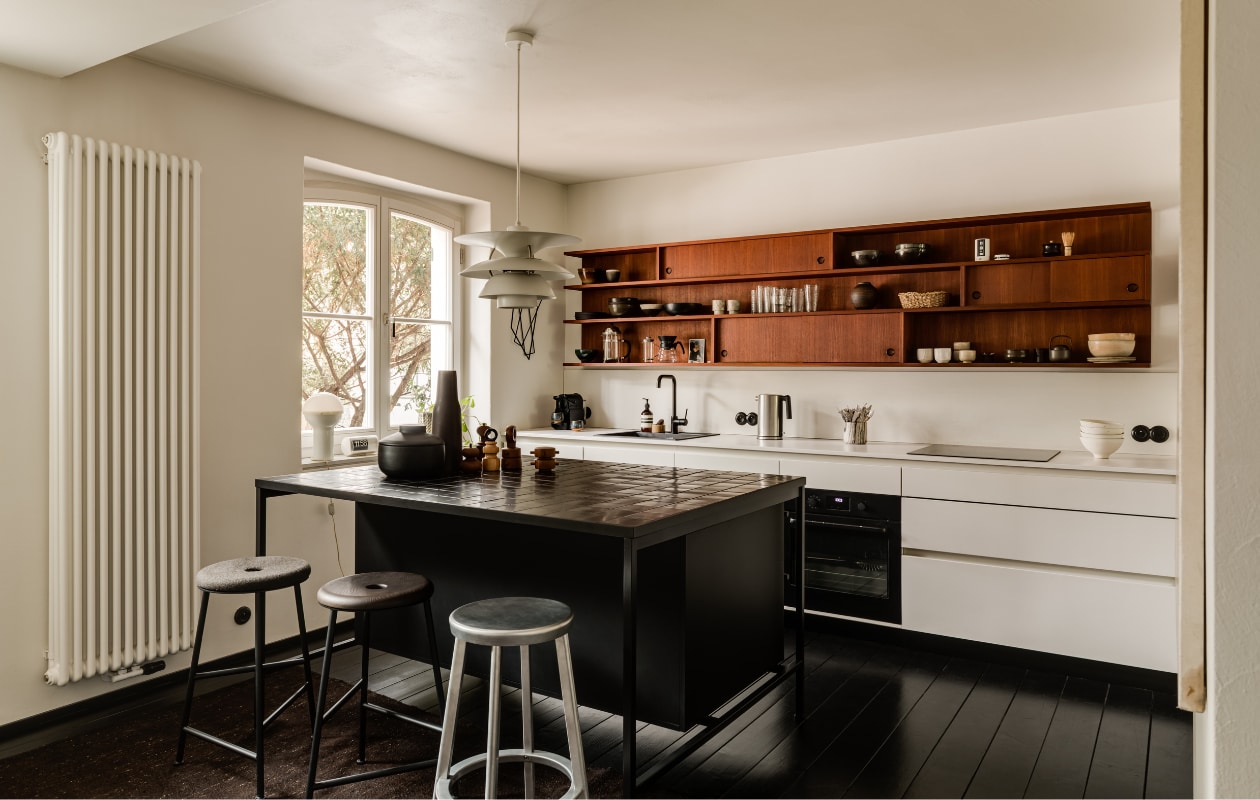 Keukeneiland ontworpen door Piotr Kuchciński. Aluminium kruk Déjà-vu van Naoto Fukasawa voor Magis. Zwarte krukken Rotor van Piotr Kuchciński voor Noti. Vintage lamp Ph 5-4 ½ van Poul Henningsen voor Louis Poulsen. Teak bovenkasten met legplanken, vintage. stijlvol wonen 10-2025 | fotografie oni studio