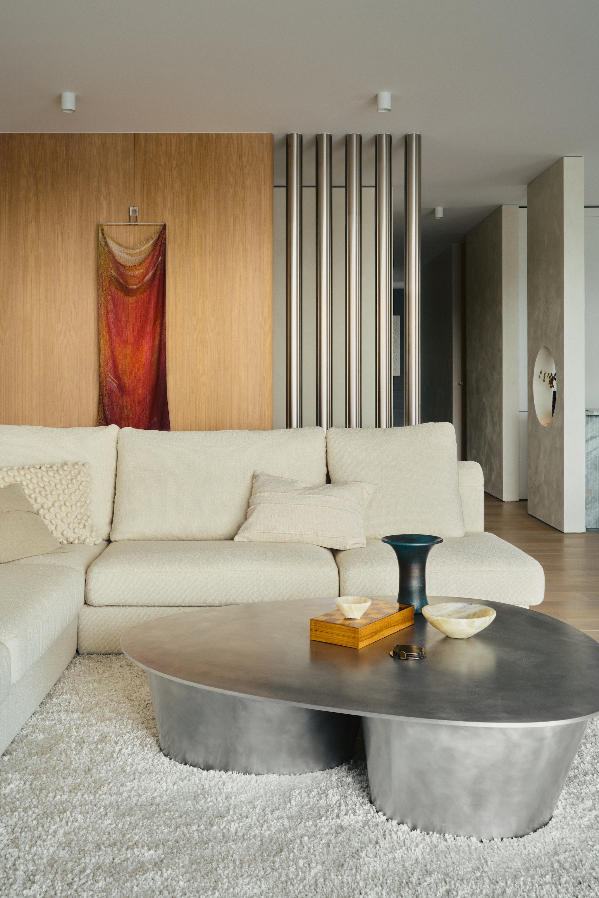 Hoekbank Nobonobo. Aluminium salontafel Jan Ankiersztajn. Groene poef zelf gemaakt. Vloerkleed Roots Living. Werk aan eikenhouten muur Marta Pokojowczyk. Lamp Lars Tornøe. vtwonen Design 02-2026 | fotografie Tomo Yarmush | productie Living Inside