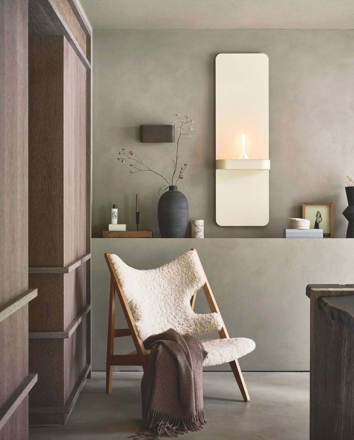 vtwonen wandhaard Glow Alto, staal, beige, 40x14,5x130 cm (bxdxh) € 799,90.M.m.v. designtales.nl (fauteuil), vachtenspecialist.nl (plaid), zarahome.com (dienblad). Overig privébezit. vtwonen 12-2025 | styling Sanne Ketelaar | fotografie Sjoerd Eickmans