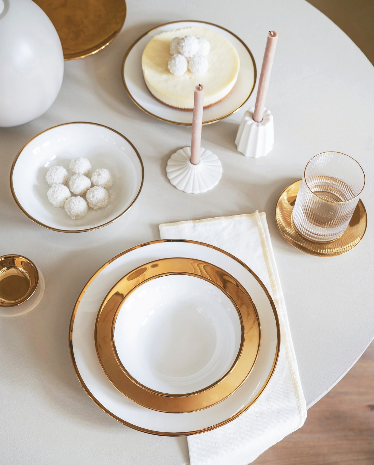 vtwonen kandelaars, keramiek, wit, sets van 4, vanaf € 25,-, vtwonen kommen, porselein, wit-goud, vanaf 15 cm (Ø), set van 4 € 35,-, vtwonen bord, porselein, wit-goud, 25,5 cm (Ø), set van 2 € 25,-, vtwonen bord, porselein, goud, 20 cm (Ø), set van 4 € 35,-, vtwonen waterglas, geribbeld glas met gouden rand, 340 ml, set van 4 € 29,-,  vtwonen petit four borden, porselein, goud, 12 cm (Ø), set van 4 € 24,95, vtwonen schaaltje, porselein, goud, 7 cm (Ø), set van 4 € 14,95. Overig privébezit. kerstboek 2025 | styling Sanne Ketelaar | fotografie Stan Koolen