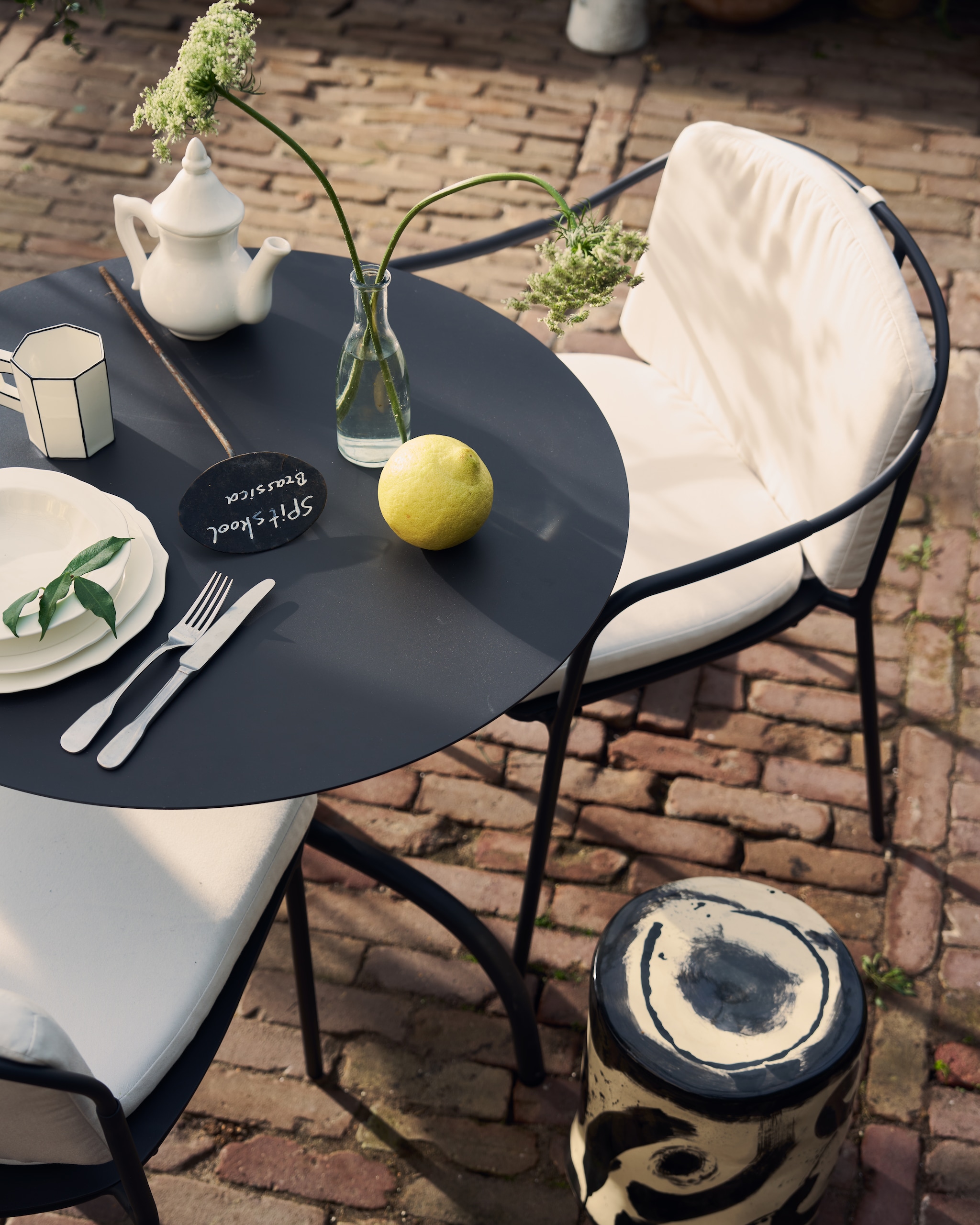 Serax stoel Patio, aluminium, zwart € 370,-, stoel Patio met armleuningen, aluminium, zwart € 390,-, stoelkussen Patio € 100,-, tafel Patio, aluminium, zwart, 75x73 cm (Øxh) € 395,-, borden Silhouette, porselein, wit, vanaf € 8,50, bijzettafel 06 Sophia Pawn, keramiek, zwart-wit, 27x34 cm (Øxh) € 190,-, beker Carte Blanche, porselein € 22,- (serax.com). Household Hardware theepot € 49,- (householdhardware.nl). Kn Industrie bestek Brick Lane, rvs, met lepel € 7,-, vork € 7,- en  mes € 12,- (bymolle.com). Overig privébezit. vtwonen 03-2026 | styling Cleo Scheulderman | fotografie Jeroen van der Spek