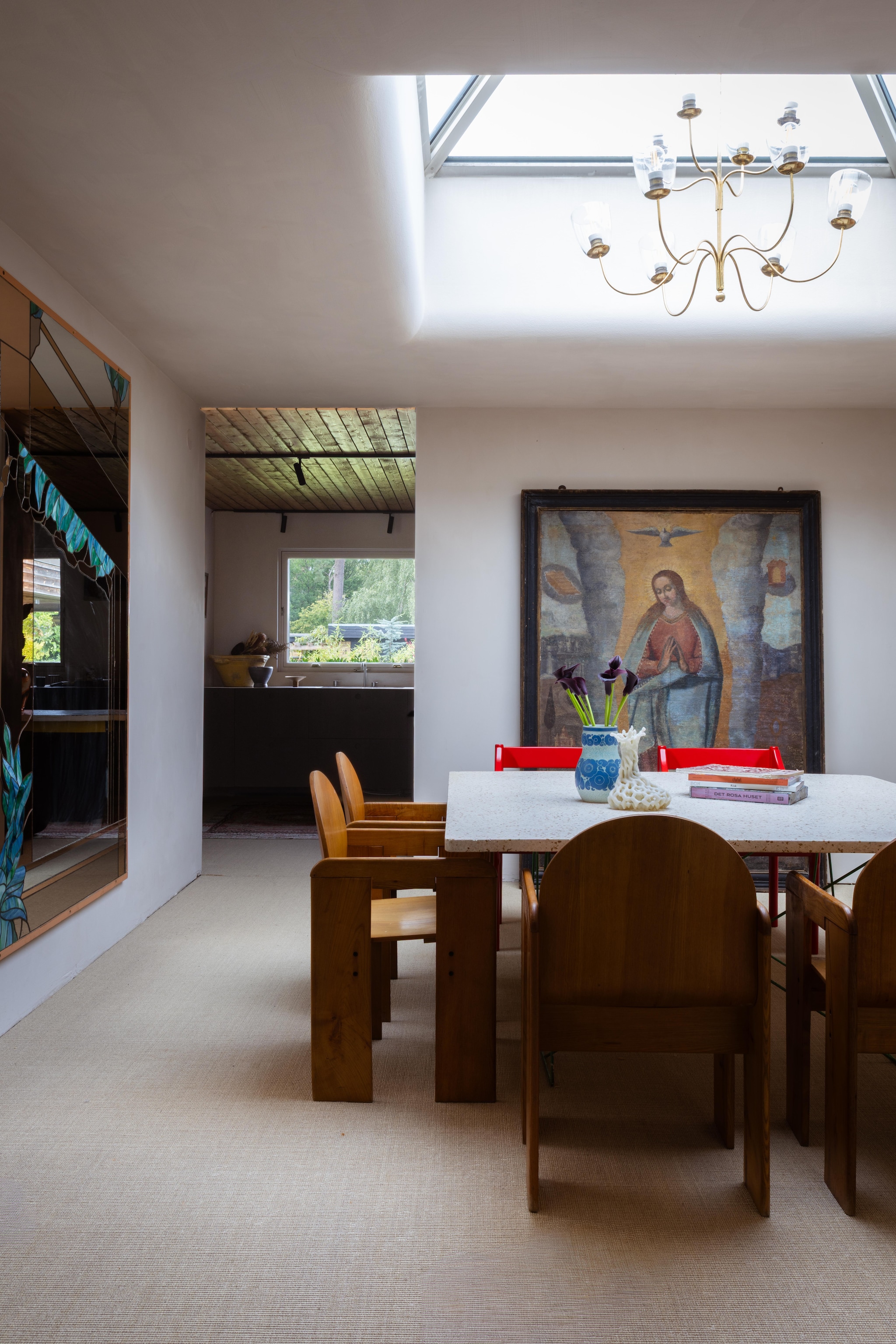 Houten stoelen Scarpa. Rode stoelen Magistretti. Vaas Rörstrand. Zeventiende-eeuws schilderij uit Mallorca. Venetiaanse spiegel vintage. Italiaanse kroonluchter vintage. vtwonen Design 03-2026 | fotografie Monica Spezia | productie Living Inside