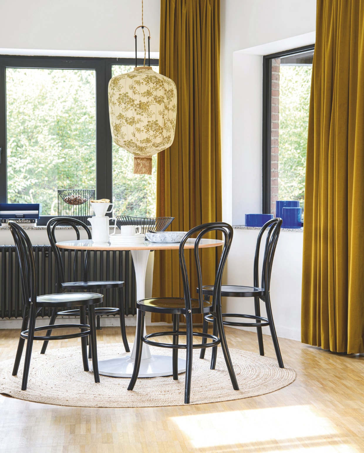 Lamp HKliving. Tafel vintage. Blauwe vazen rommelmarkt. Fluwelen gordijnen Hema. Stoelen, marmeren fruitschaal, servies en tafellamp Zangra. Soortgelijk vloerkleed Mrcarpet. vtwonen 12-2025 | styling Marit Saladini | fotografie Louis Lemaire