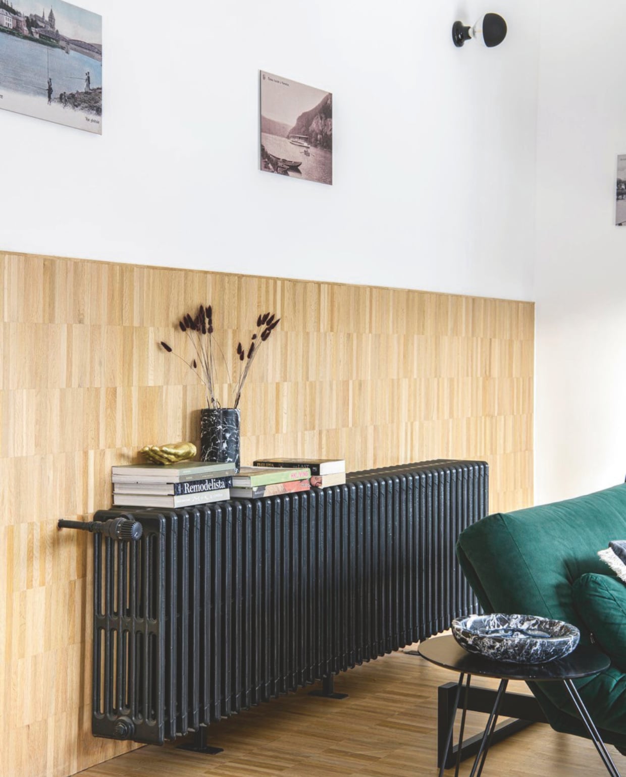 Radiator zat al in het huis, zwart geverfd. Wandlamp Zangra. Bijzettafel vintage. Aan de muur oude foto’s van Hastière, uitvergroot en op aluminium geplakt. vtwonen 12-2025 | styling Marit Saladini | fotografie Louis Lemaire