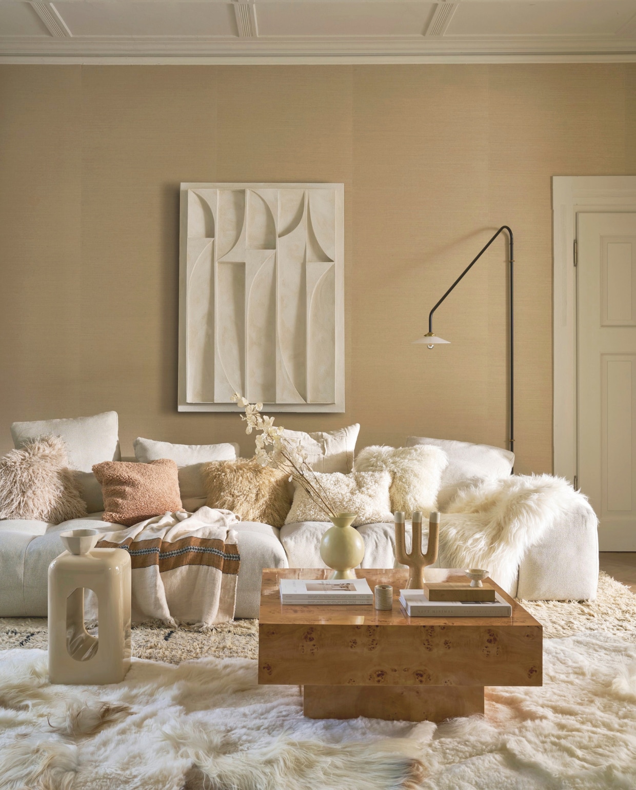 Art in Return kunstwerk, offwhite, 140x100 cm (lxb), prijs op aanvraag (artinreturn.nl). Dutchbone salontafel Quinn, wortelhoutfineer met glanzende lak, 90x90x39 cm (lxbxh) € 695,- (dutchbone.com). Zuiver bijzettafel Creek, kunststof, beige hoogglans, 29x29x48 cm (lxbxh) (zuiver.com). Urban Nature Culture vaas Kudos, keramiek € 49,99, kandelaar Nox, keramiek, beige € 49,99, kommetje Lav op voet, keramiek, beige € 9,99 (shop.vtwonen.nl). Vachtenspecialist schapenvacht vloerkleden, melange wit, 180x120 cm (lxb) € 695,-, kussen Tibet, lamsvacht, offwhite en camel, 45x45 cm (lxb) € 64,95, schapenvacht IJslands, op bank, wit € 79,95 (vachtenspecialist.nl). Saba Italia bank Pixel, 296x136x65 cm (lxbxh), prijs op aanvraag (kasstoor.nl). Valerie Objects wandlamp nr 4, door Muller Van Severen, metaal en glas, zwart, 180x90 cm (lxb) € 880,- (mudinmay.nl). Libeco deken Highland Stripe, linnen, beige-bruin, 140x220 cm (lxb) € 336,- (sukha.nl). Zara Home kussenhoes, teddy crème, 60x40 cm (lxb) € 25,99, kom, keramiek, zand € 9,99 (zarahome.com). H&m Home kussenhoes Teddy, lichtbruin, 50x50 cm (lxb) € 19,99, kussenhoes Fluffy, beige € 24,99 (hm.com). Phillip Jeffries behang Manila Hemp 9820, kleur plaster, 91,4x732 cm (bxl) per rol, prijs op aanvraag (phillipjeffries.com). vtwonen 12-2025 | styling Cleo Scheulderman | fotografie Jeroen van der Spek