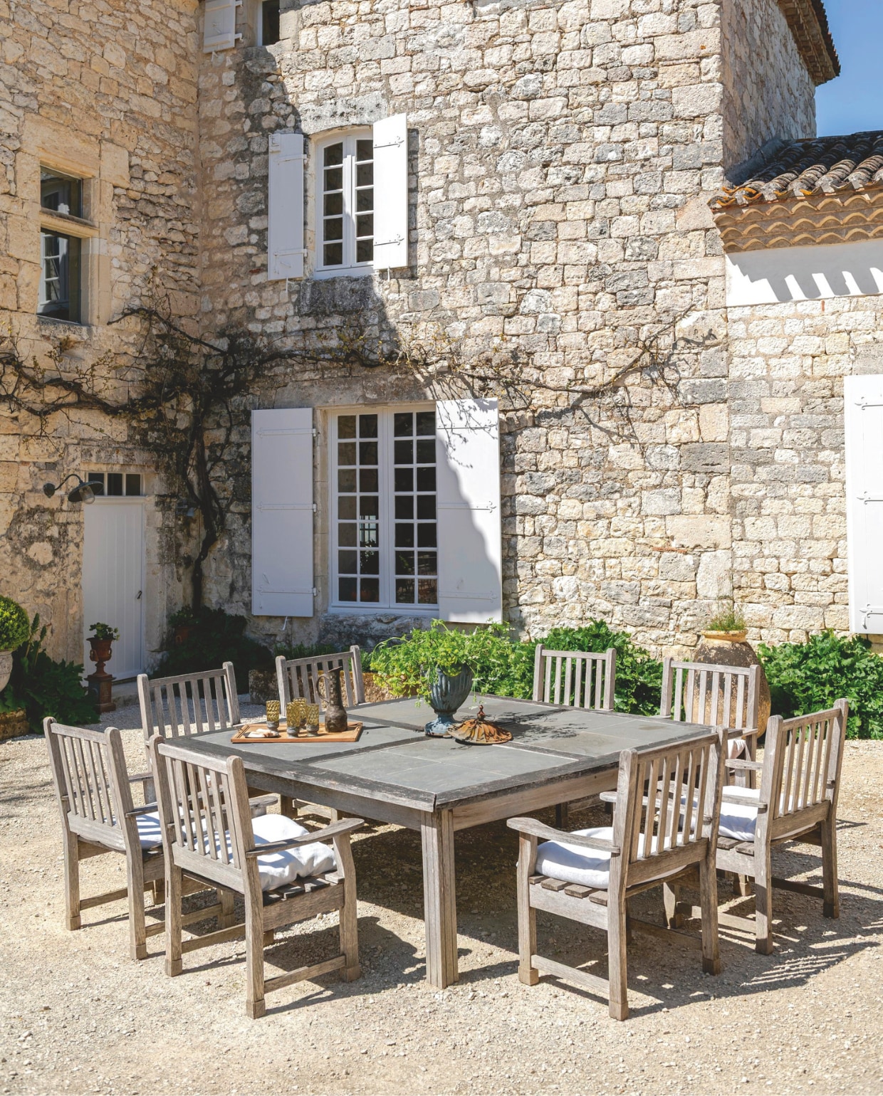 Teakhouten tafels en stoelen gemaakt door Reginalds vader. De Medici-vazen bij de ingang komen uit Nederland. Soortgelijke bij De Briellaerd. vtwonen Landelijk 12-2025 | styling Amandine Berthon | fotografie Julien Fernandez