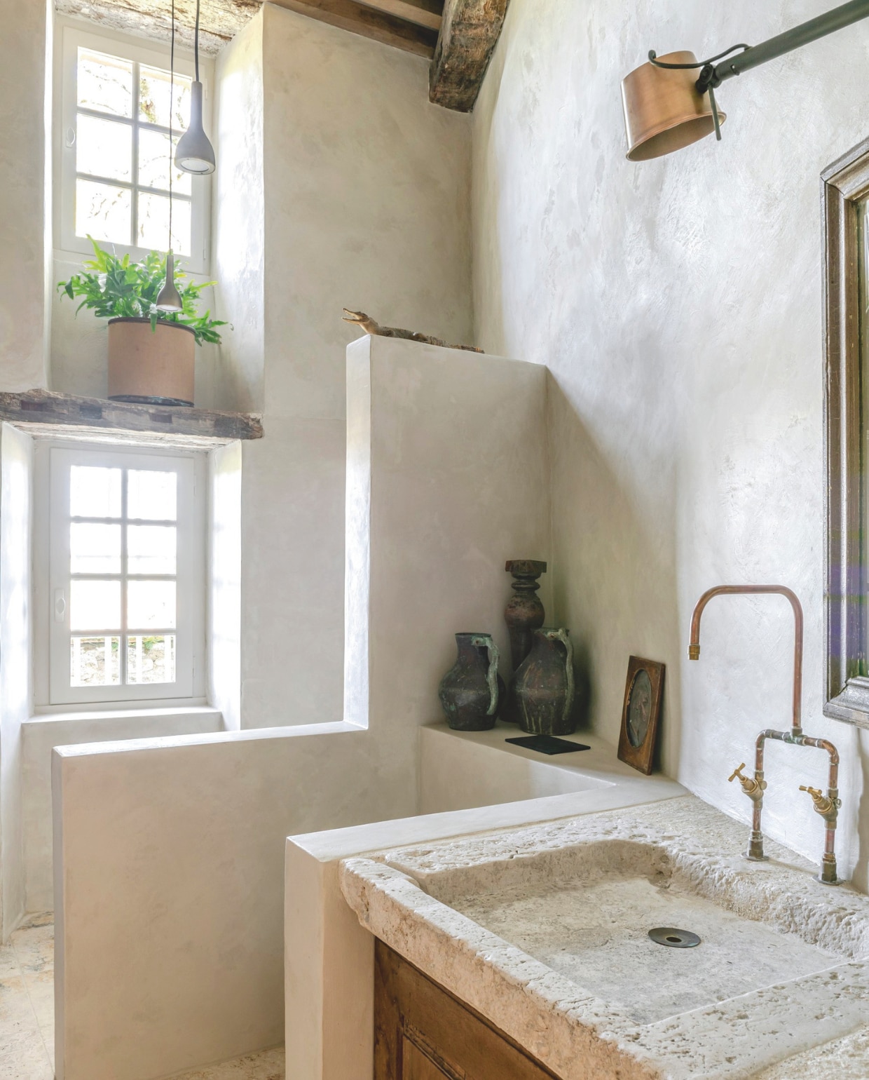 Wastafelmeubel gemaakt door Reginald van een oude kastdeur en een vintage stenen wasbak. Ook de kranen maakte hij. Lampen Frezoli Lighting. vtwonen Landelijk 12-2025 | styling Amandine Berthon | fotografie Julien Fernandez