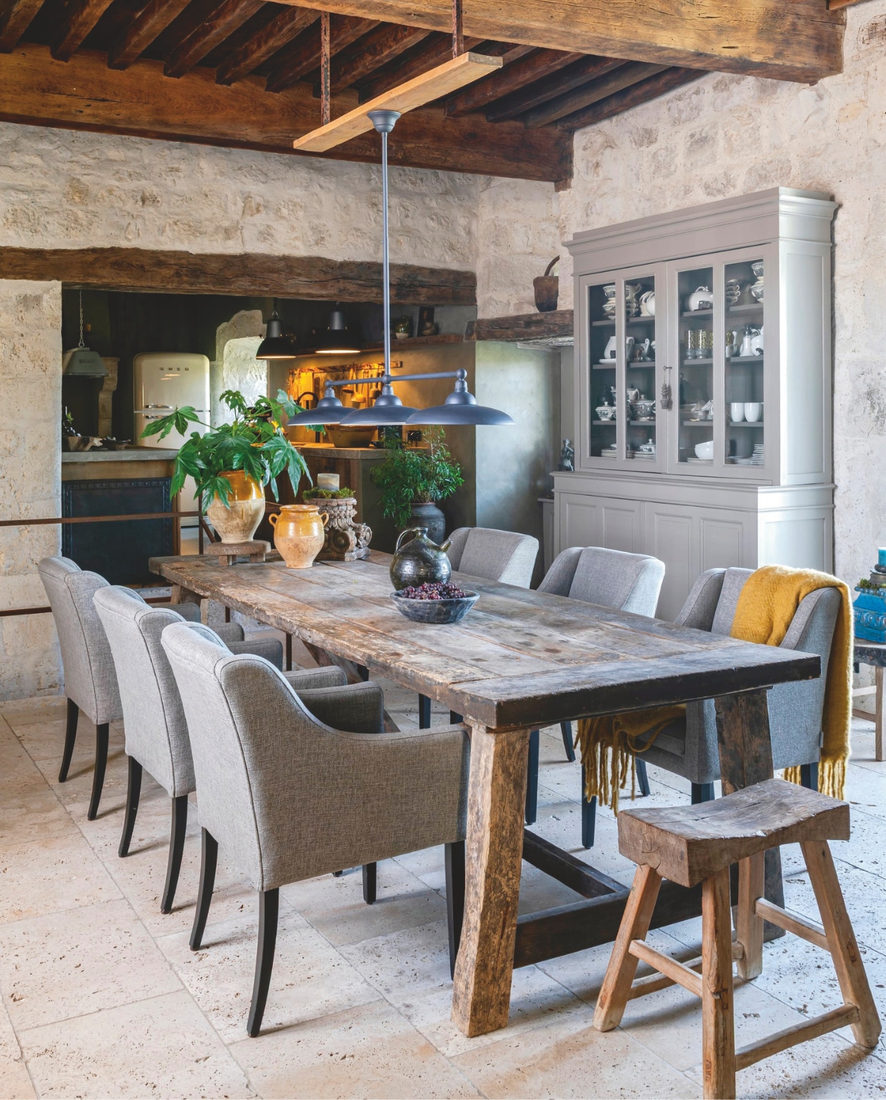 Eettafel Cerca Trova. Dressoir, potten en schalen rommelmarkten. Stoelen Bocx Interiors. Hanglamp Frezoli Lighting. Kruk en plaid Goround Interior. Decoratieve objecten vintage. vtwonen Landelijk 12-2025 | styling Amandine Berthon | fotografie Julien Fernandez