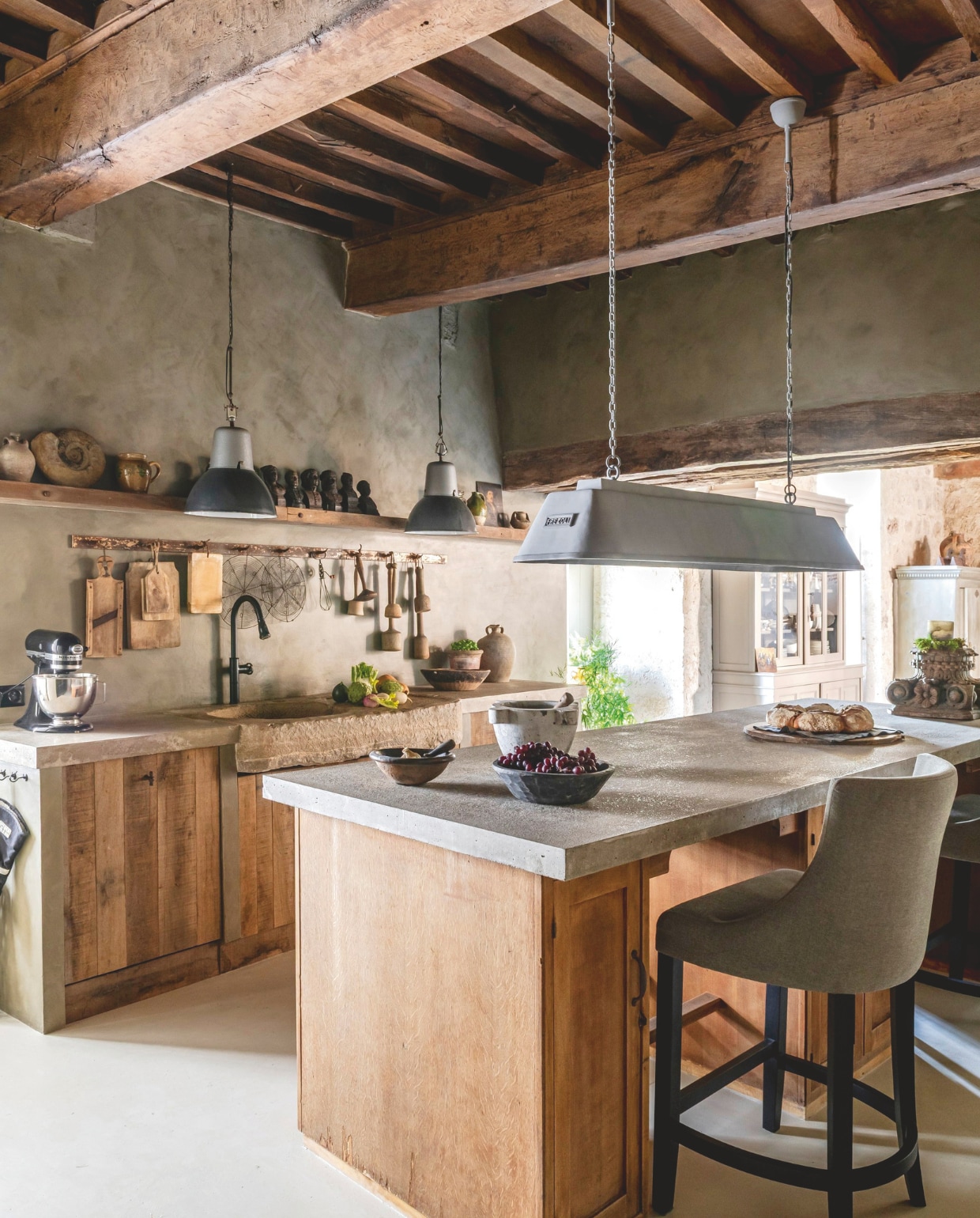 Barkrukken Bocx Interiors. Mixer Kitchenaid. Het eiland is een oud postkantoor-bureau met een werkblad van gegoten beton. Lamp erboven Bizz van Frezoli Lighting. Muurverf Tundra van Pure & Original.  Soortgelijke zwarte hanglampen Iron and Wood. vtwonen Landelijk 12-2025 | styling Amandine Berthon | fotografie Julien Fernandez