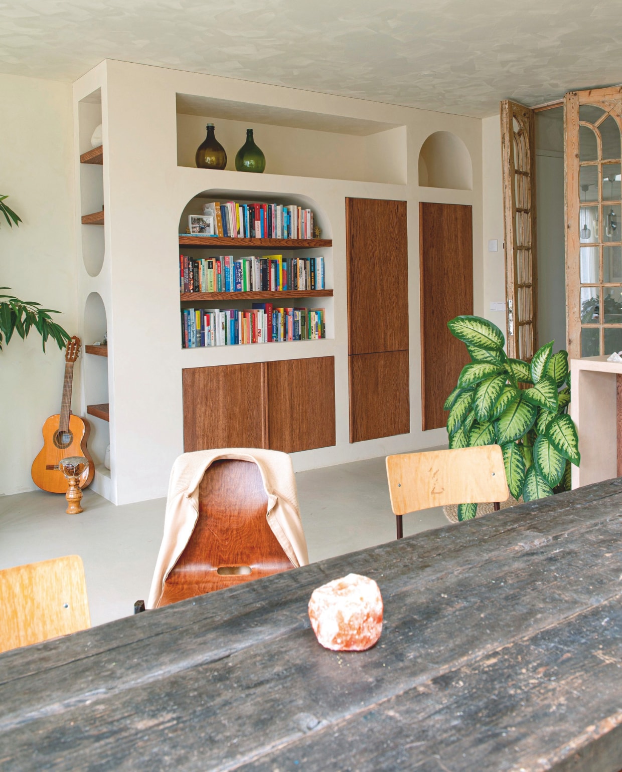 Verf wanden en plafond Mykonos van We Are Wow Makers. Vloer van klei van Creative Plasters. Kast zelf ontworpen en gemaakt door David Hansen Interieur. Tafel en stoelen kringloop. Vazen in kast Burbri Antiek. Tussendeuren Empire. Gitaar en trommel tweedehands.Waxinelichthouder zoutsteen Fabula Rosa. vtwonen 12-2025 | styling Annemieke Paarlberg | fotografie Caroline Coehorst | tekst Ina Babbé