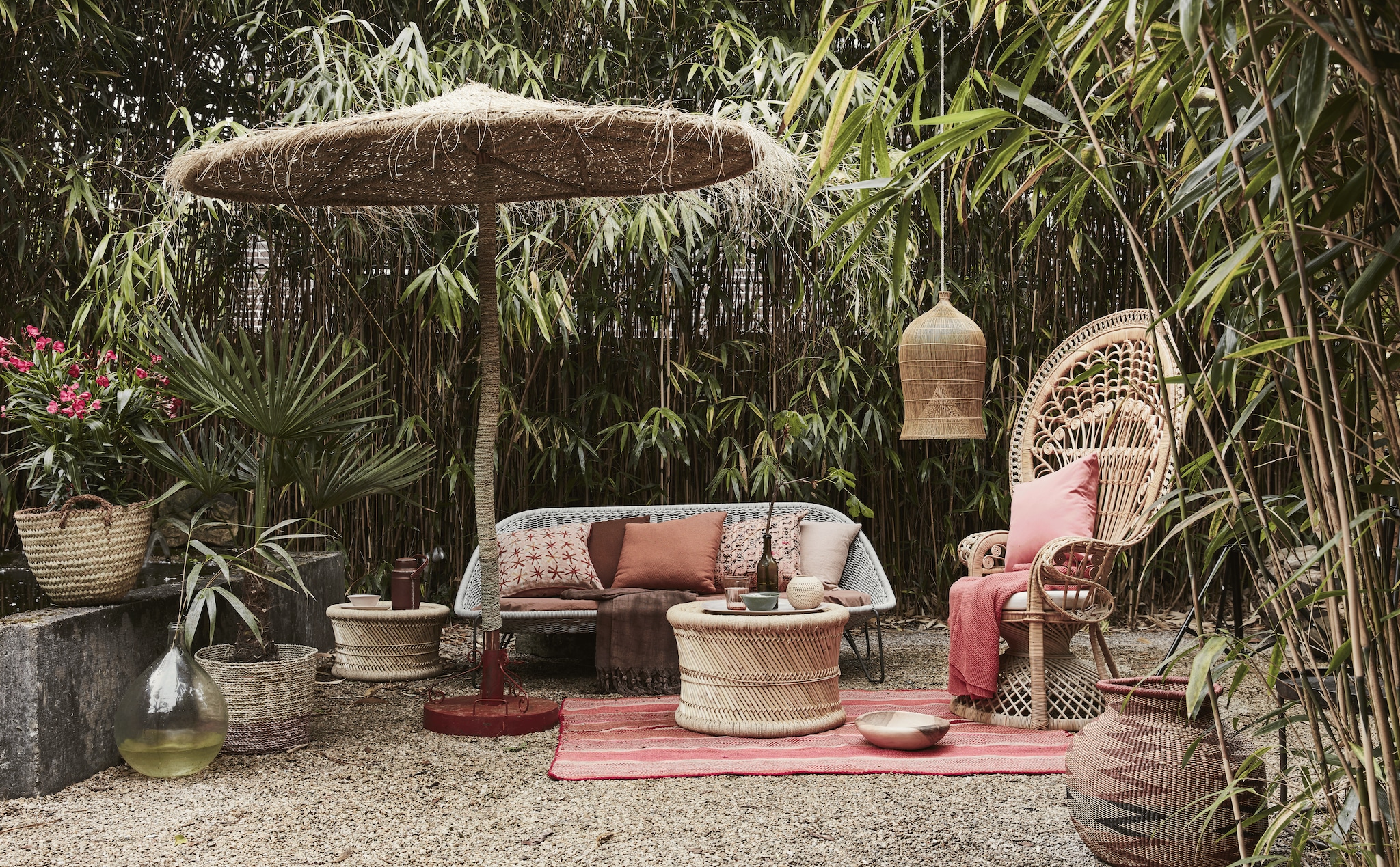 Bank Pasturo van Borek, bruinrood buitenkussen en zalmkleurig buitenkussen (Dacks). Pauwenstoel, gevlochten poefjes (Zenza). Parasol met voet, roze gestreept vloerkleed, visfuik als lampion, houten schaal, mand op het muurtje, gevlochten pot met bordeauxrood zigzag dessin (Couleur Locale). Flamingo-roze plaid, zachtroze linnen kussen (By Mölle). Groene kom, grote schaal, fles, leren thermosfles, gedessineerde kussens, grote glazen fles (Meker Wonen), bordeauxrode linnen plaid (L’Etoile Conceptstore). Mand met roze bodem (Sissy-Boy).
