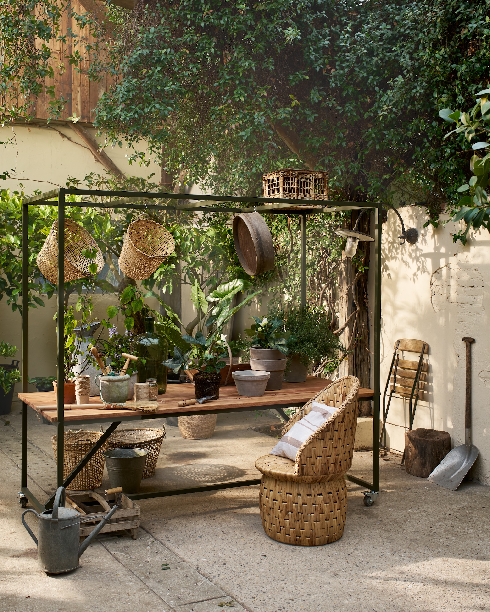 Buitentafel op wielen Blue Sky in Camouflage Groen, hout en aluminium, 200x97x220 (lxbxh) € 599,-.M.m.v. nordal.dk (gevlochten stoel), madamstoltz.nl (manden, bezem op tafel), Iblaursen.nl (kussen). vtwonen special 01-2026 | fotografie Jeroen van der Spek | styling Cleo Scheulderman