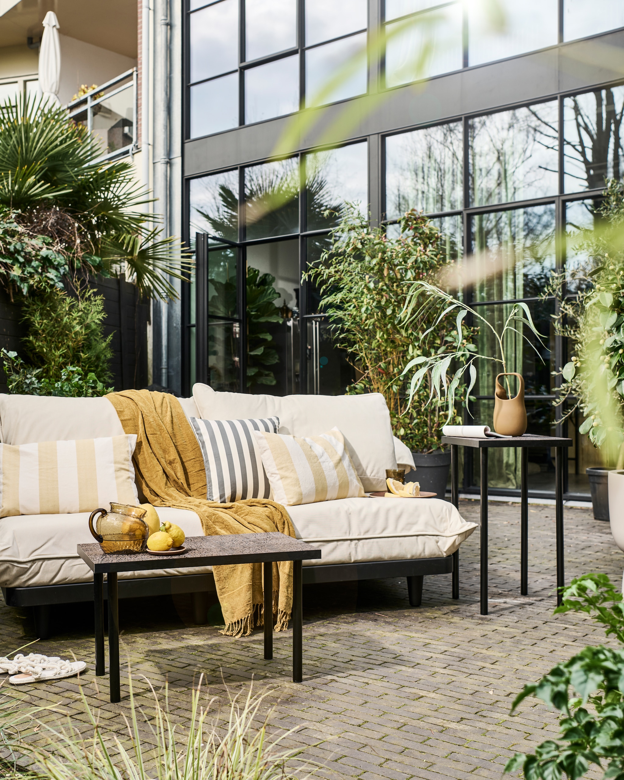 Modulaire loungeset Paletti van Fatboy, kunststof frame met waterafstotende kussens € 899,-, bruine stenen vaas Nicita van Bloomingville € 58,90 (vtwonen.nl/shop). Plaid € 12,99, blauw gestreept kussen € 17,99, geel gestreept kussen € 17,99, glazen karaf € 29,99, houten onderzetter € 5,99, houten dienblad € 17,99, drinkglazen € 5,99 (zarahome.com). Overig privébezit.