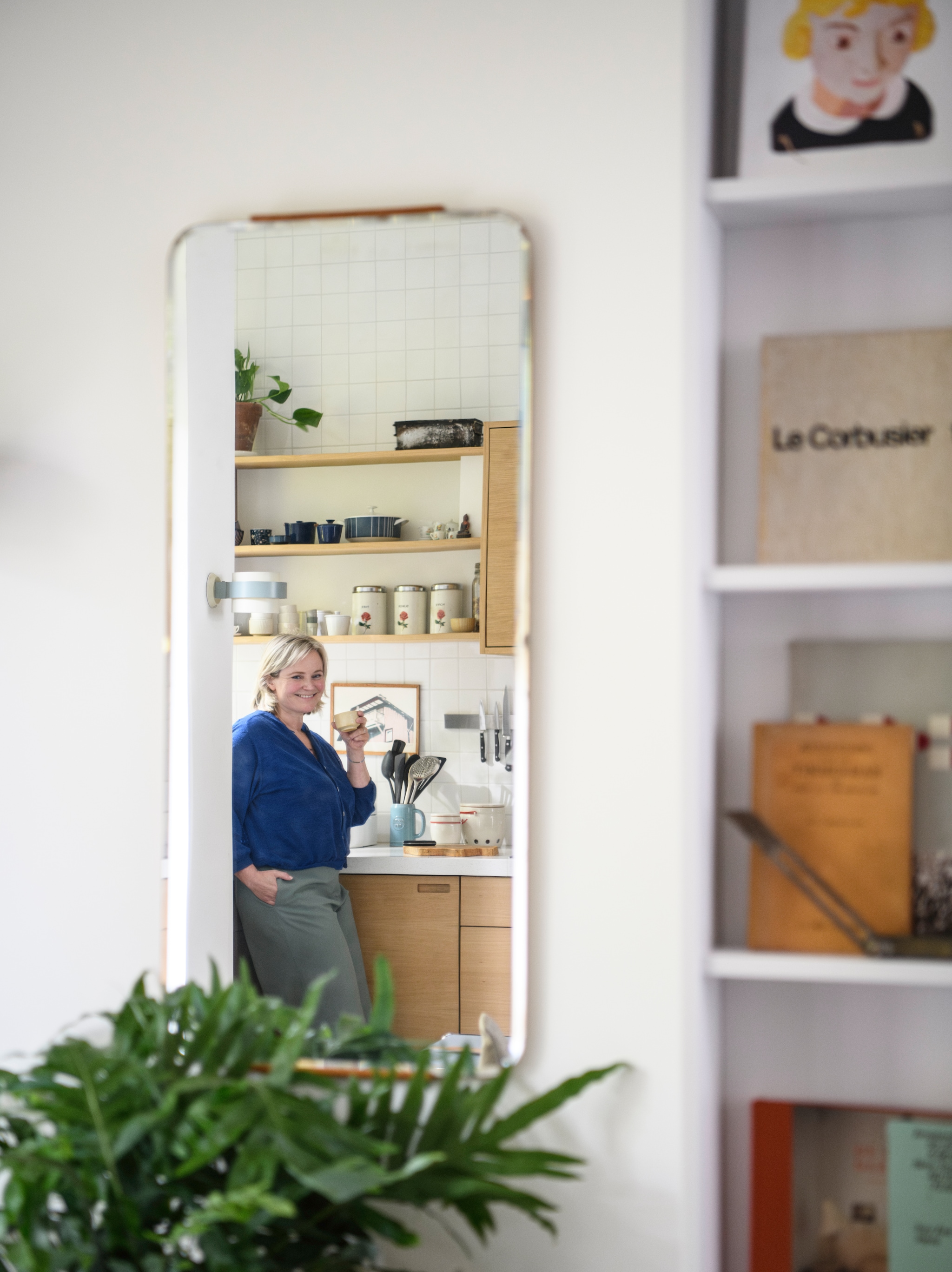 Spiegel en wandlamp Louis Kalff, vintage. De keuken heeft veel planken, zodat Klaartje al haar brocante spullen kan uitstallen. vtwonen 04-2026 | styling Kim Timmerman | fotografie Louis Lemaire | productie Insidehomepage