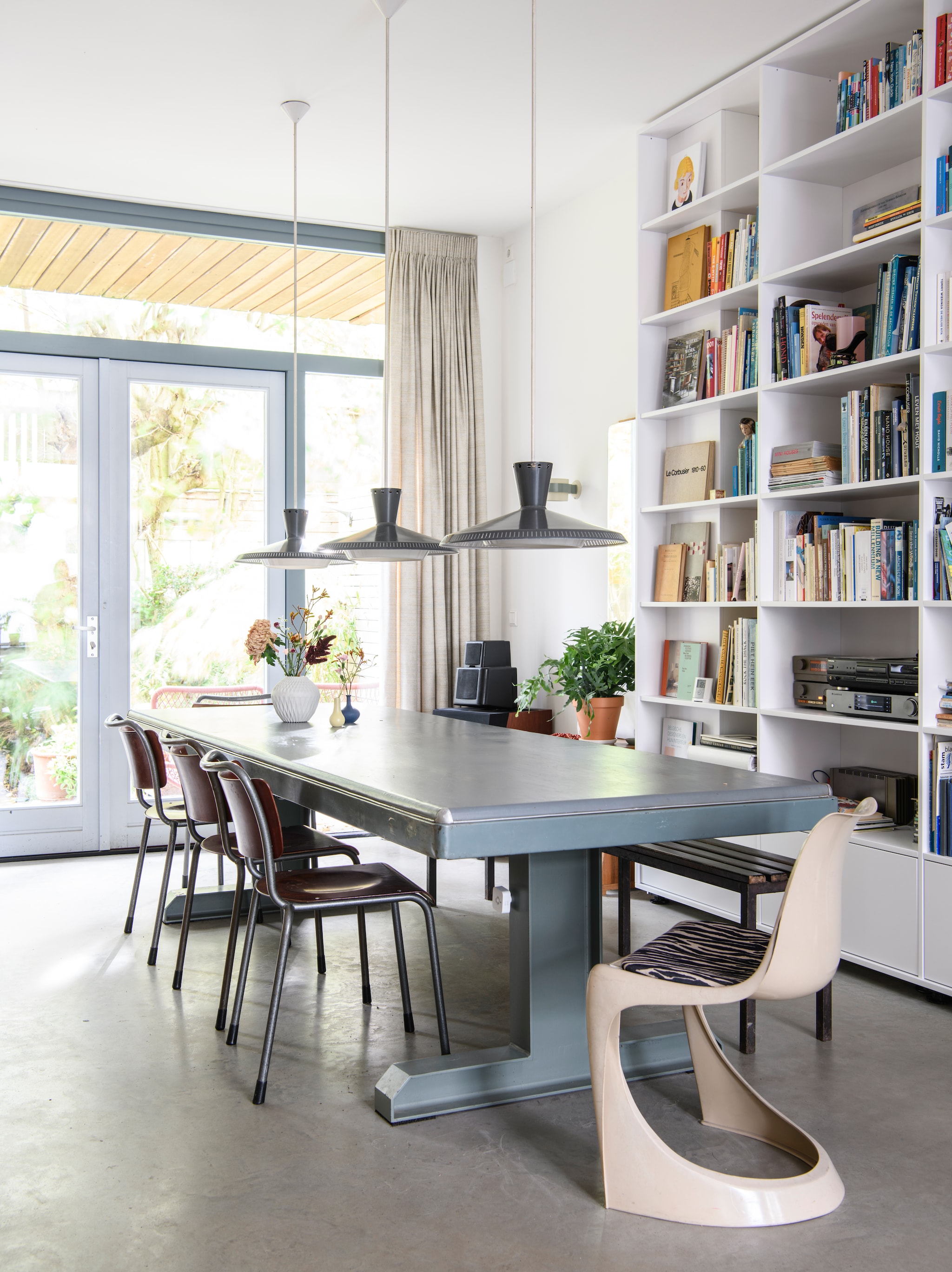 De onderkant van het balkon bekleedde Stijn met restanten hardhout. Eettafel gemaakt van een oud bureaublad en zelf ontworpen tafelpoten. Stoel aan hoofd vintage. Stoelen Tu Delft van Gispen. Hanglampen en wandlamp Louis Kalff, vintage. Vaas Lenneke Wispelwey. Gordijnen De Ploeg. vtwonen 04-2026 | styling Kim Timmerman | fotografie Louis Lemaire | productie Insidehomepage