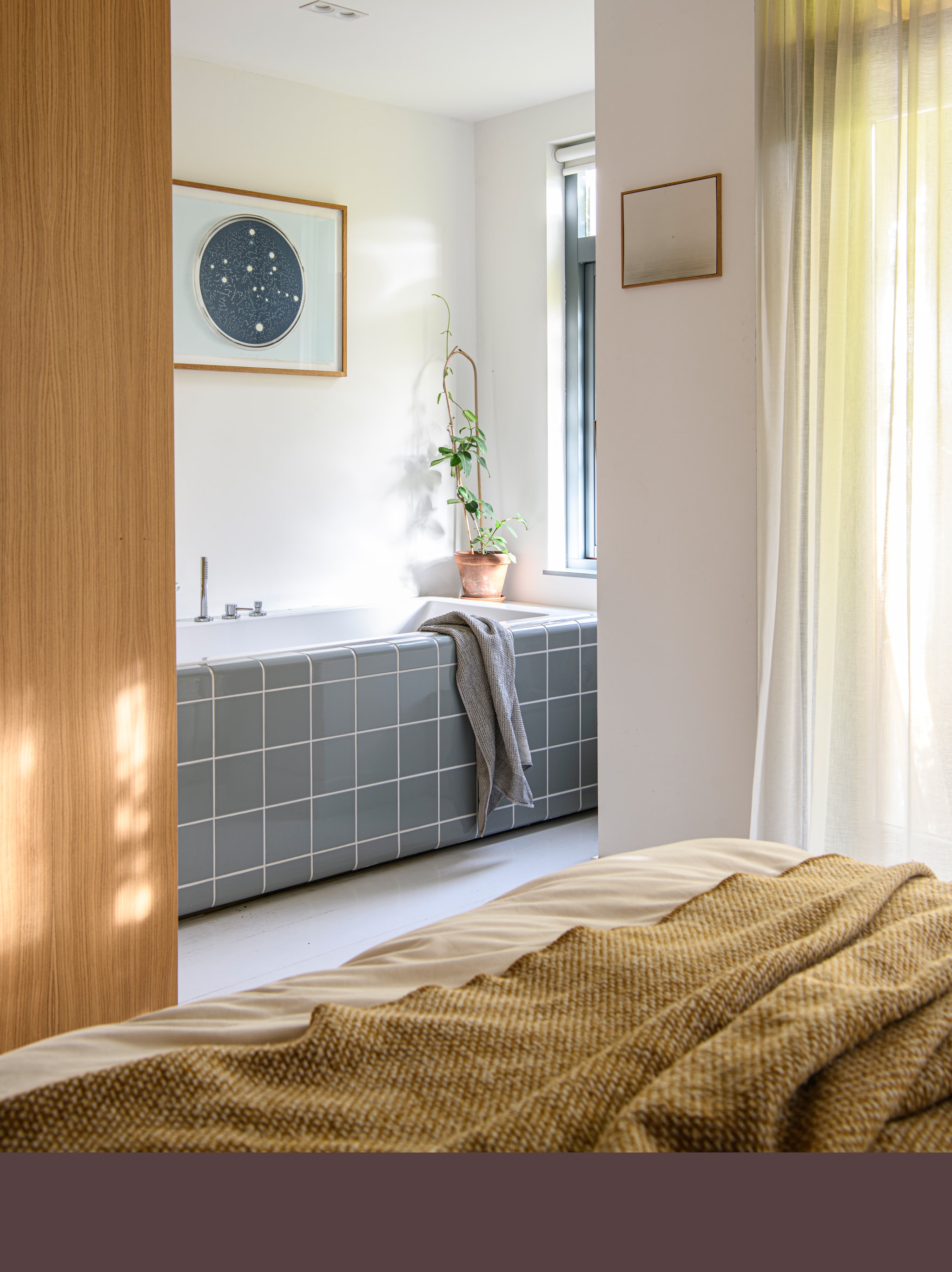 In een hoek van de slaapkamer maakte Stijn een nieuw raam zodat hij kon badderen in het daglicht. Alles maatwerk. Tegels Dtile in kleur 22 Tuinboon. Kunstwerk Pieter van der Veen.  vtwonen 04-2026 | styling Kim Timmerman | fotografie Louis Lemaire | productie Insidehomepage