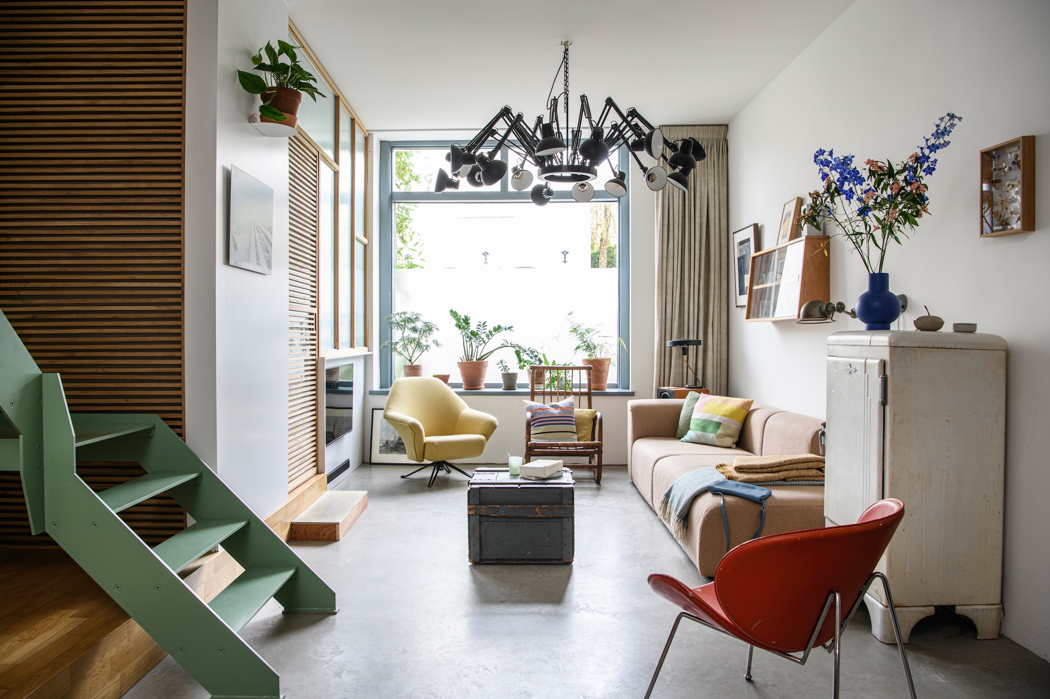 Plafondlamp Dear Ingo van Ron Gilad voor Moooi. Gele stoel Osvaldo Borsani, erfstuk van Klaartjes grootouders, opnieuw bekleed. Gordijnen De Ploeg. Rode stoel brocante. Bank Hay. Kussen Manufactum. Oude koelkast omgebouwd tot kast. Bijzettafel oude munitiekist. Wandlamp Jieldé. Kunstwerk links Tamasine McNabb. Rotan stoel, vitrinekast en tafellamp vintage. Klein kunstwerk Danièle Knirim. Vaas Raawii. Trap ontworpen en gemaakt door Stijn. Lattenwand en kozijnen gemaakt van afvalhout.