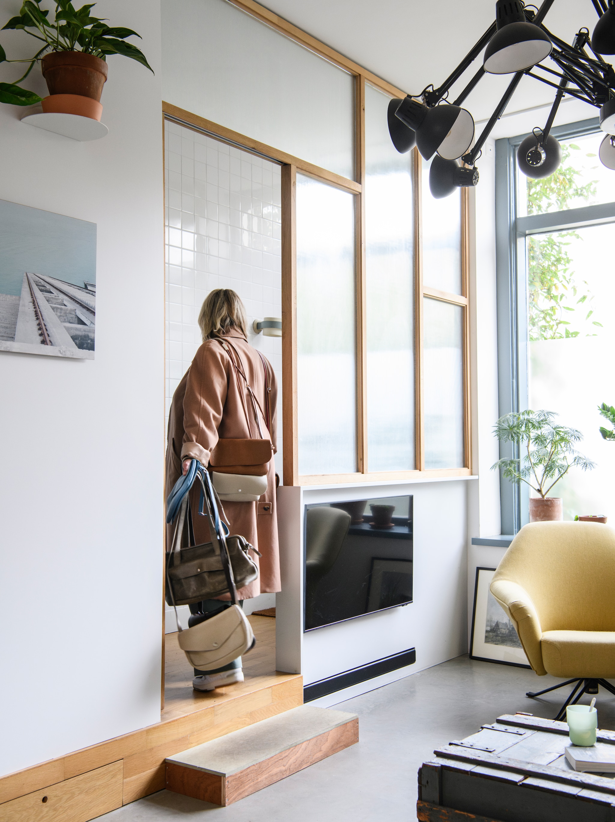 Klaartje met tassen van haar label Keecie. Tegels Mosa. Wandlamp Louis Kalff, vintage. Plafondlamp Dear Ingo van Ron Gilad voor Moooi, tweedehands. Stoel Osvaldo Borsani, erfstuk van Klaartjes grootouders, opnieuw bekleed. vtwonen 04-2026 | styling Kim Timmerman | fotografie Louis Lemaire | productie Insidehomepage