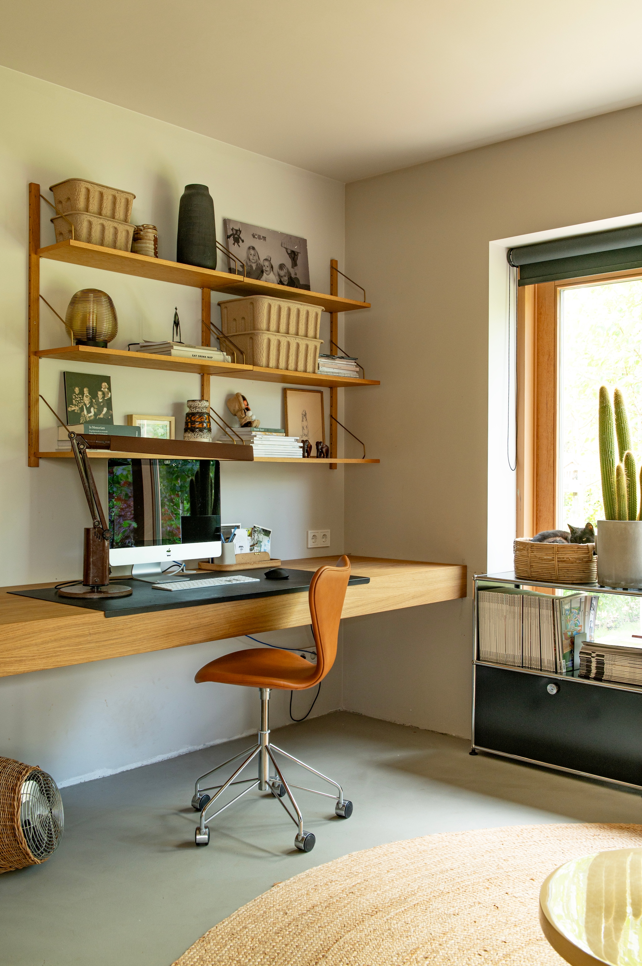 Wandrek Poul Cadovius. Lamp en zwarte vaas via Bynord. Opbergboxen Ferm Living. Vintage bureaulamp. Vintage bureaustoel Butterfly van Arne Jacobsen. Bureau maatwerk van Spijkervast. Ventilator Gervason. Lage kast Usm Haller. Rolgordijn Le Rideau. Muurverf Coffee & Cream van Pure & Original. vtwonen 04-2026 | styling Jeske Weel | fotografie Caroline Coehorst