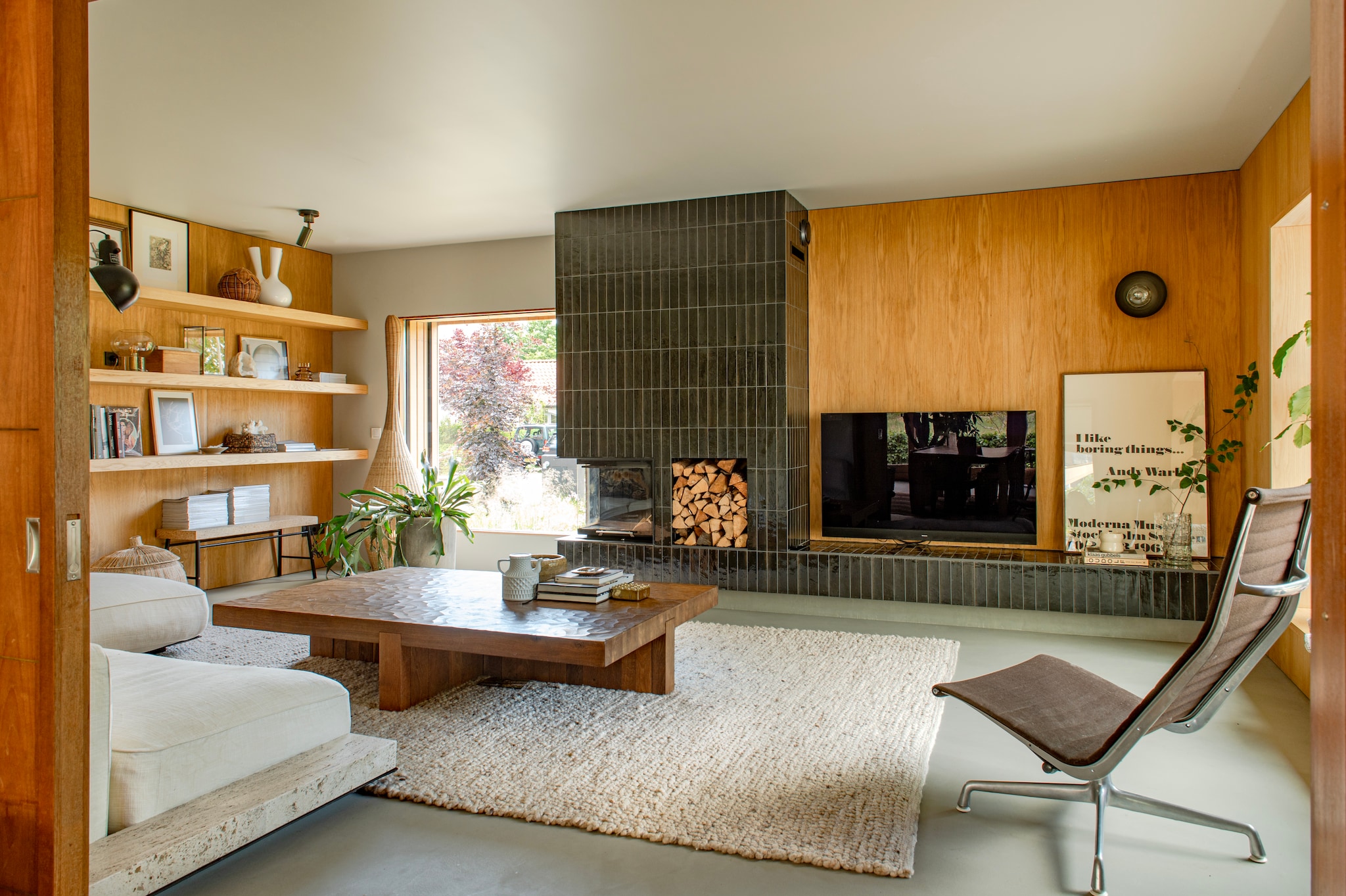 Fauteuil Charles Eames via Catawiki. Salontafel Linteloo via Whoppah. Bank Grandemare van Flexform met hergebruikt travertijn van de gesloopte schouw. Lamp Gervasoni. Tegels Lume van Marazzi. Vloerkleed, bloempot, glazen vaas en wandlamp Bynord. Poster in lijst via Moderna Museet Stockholm. Kast en wanden gemaakt door Spijkervast. Kurken bank van Ilse Crawford voor Ikea. Plafondspot Serax. Tv Panasonic. Kleur wand en plafond Old Flax van Pure & Original. Vloer Solo Gietvloeren.