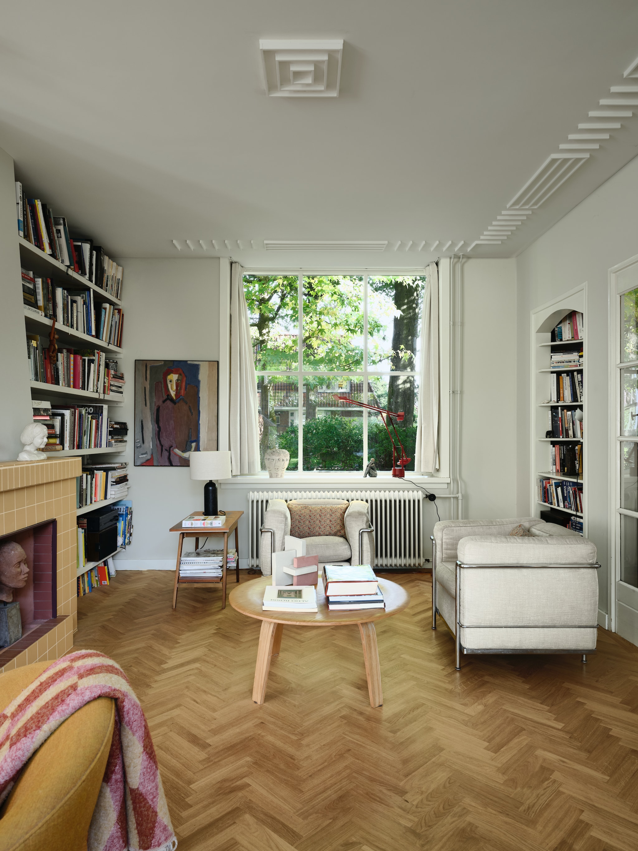 Lamp met zwarte voet Gubi. Bijzettafel vintage. Rode lamp Tizio van Artemide. Beige fauteuils Cassina Lc2 van Le Corbusier. Gele fauteuil Fried Egg van Warm Nordic. vtwonen 04-2026 | fotografie Mr. Frank