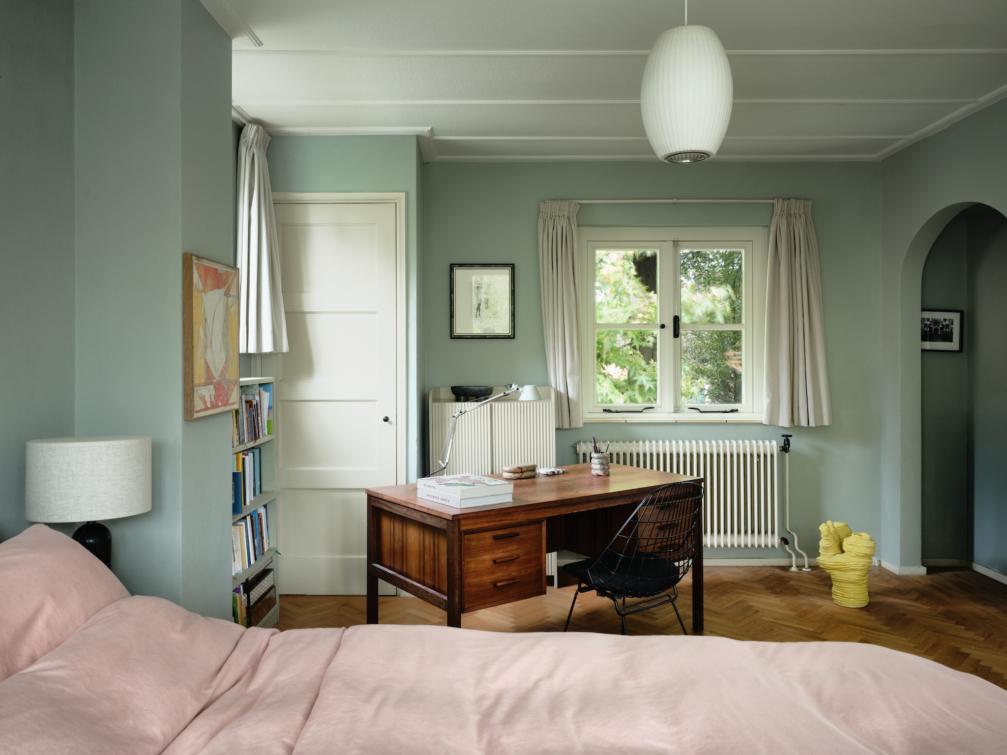 Bureau vintage. Stoel Sm05 Wire van Pastoe. Plafondlamp Nelson Bubble van Hay. Bedsprei Yumeko. Gele sculptuur Milou van Vlijmen.  Schilderij links Withdrawl Symptom #78 van Erik de Bree. vtwonen 04-2026 | fotografie Mr. Frank