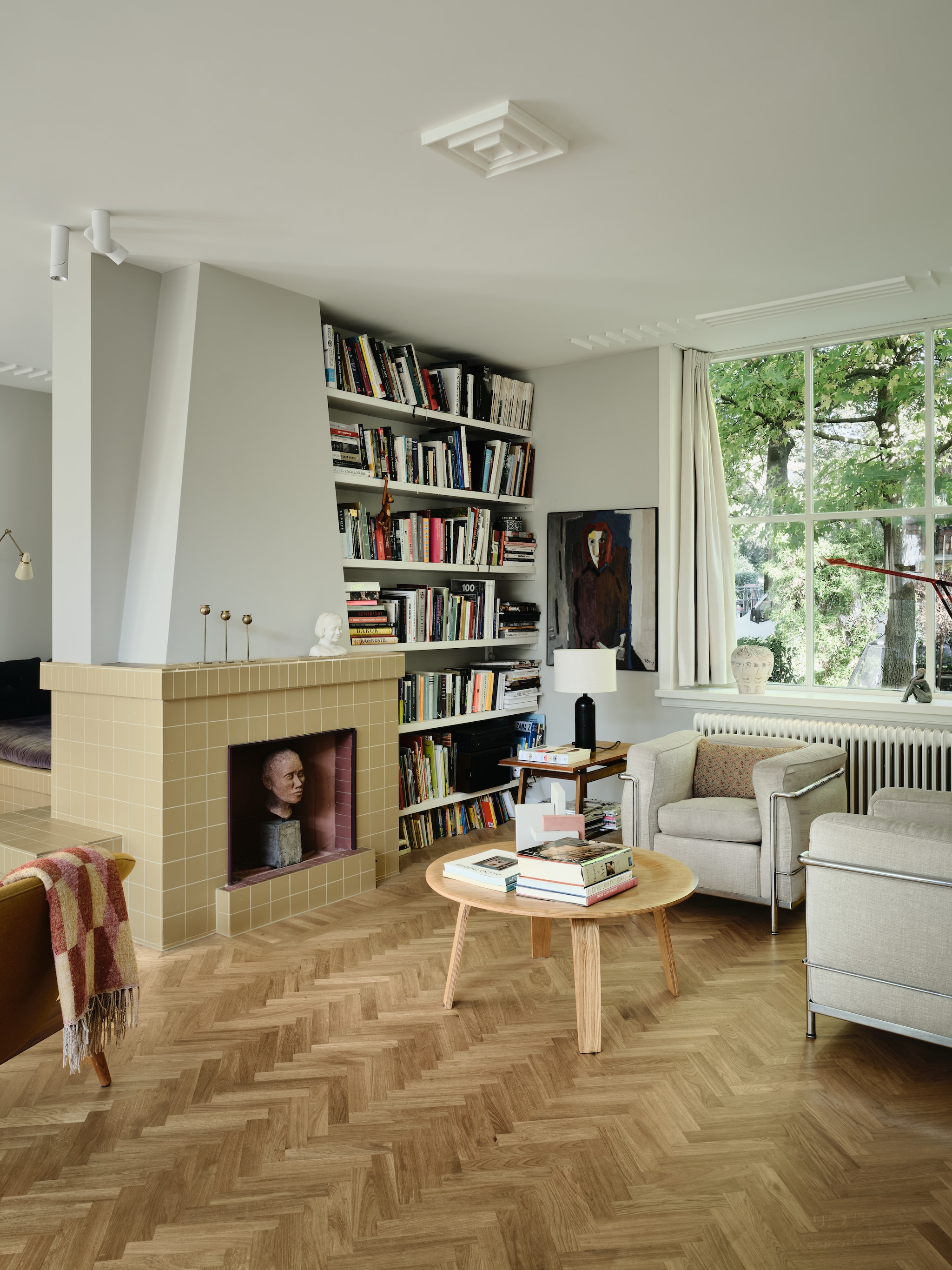 Schilderij van onbekende maker. Buste in haard vintage. Salontafel Vitra. Fauteuils Cassina Lc2 van Le Corbusier.