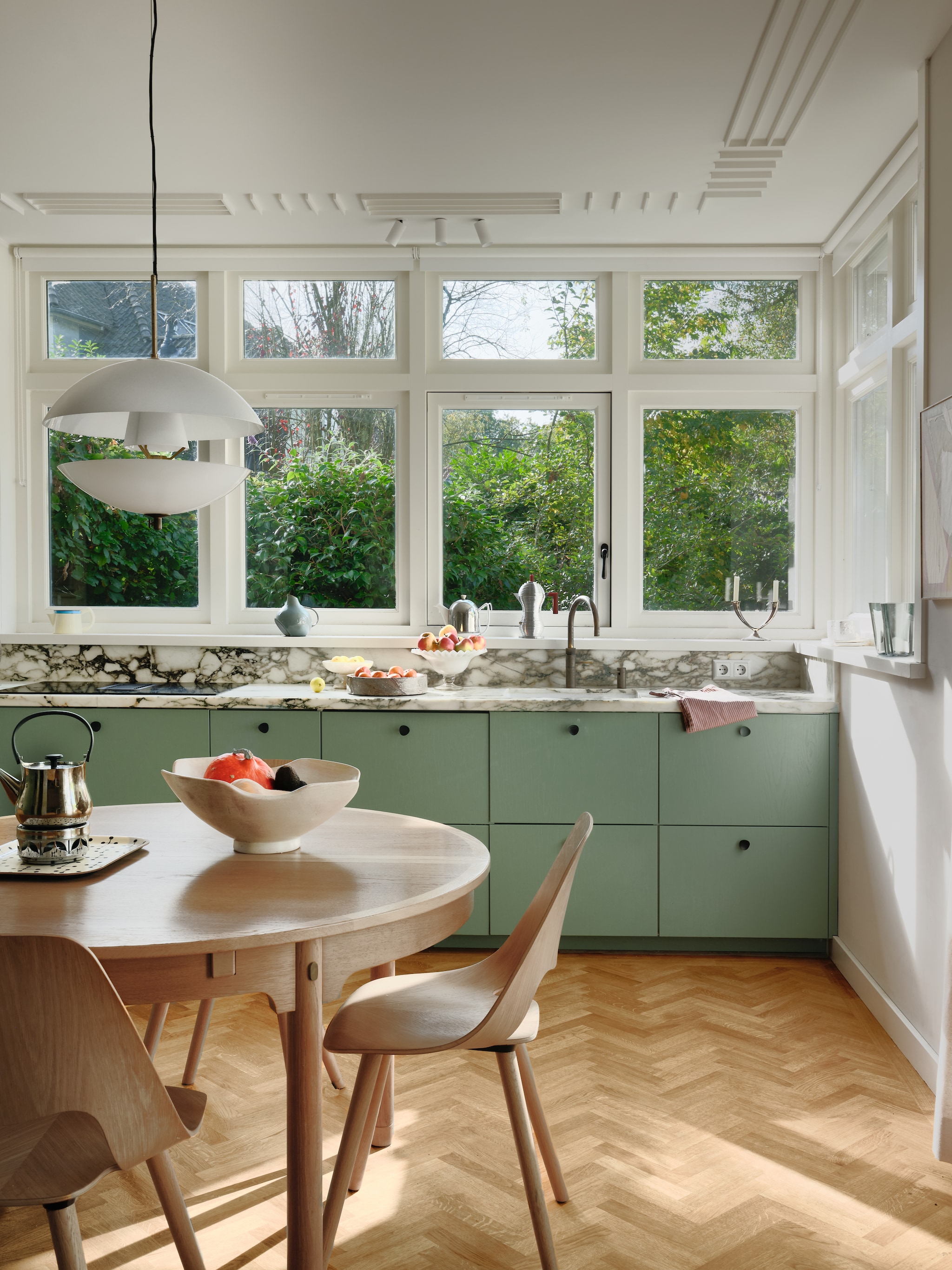 Plafondlamp Modular Lighting. Schaal op tafel vintage. Eettafel Børge Mogensen voor Karl Andersson & Söner. Stoel Jill Wood van Vitra. Keukenkasten op maat gemaakt. Marmeren blad De Keukenbladenfabriek. vtwonen 04-2026 | fotografie Mr. Frank