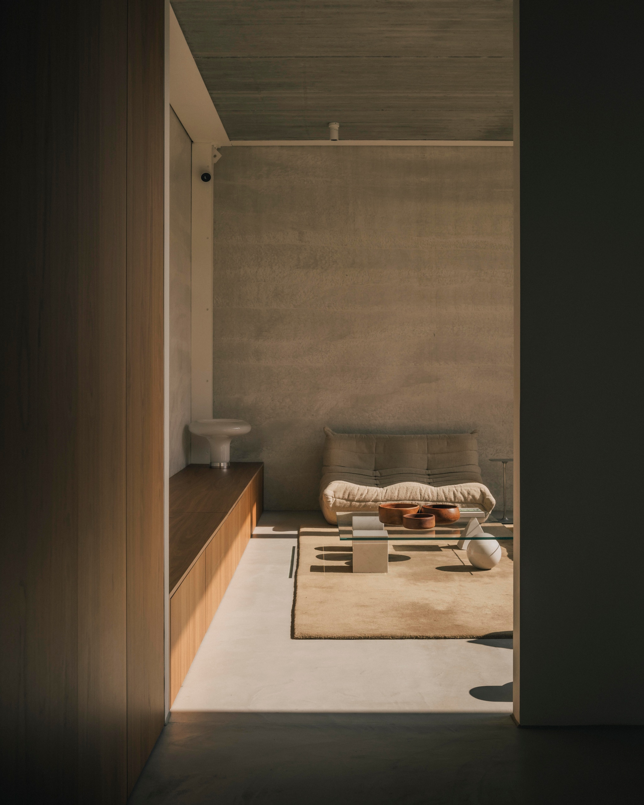 De tv-kamer met maatwerk kasten met fronten van walnoot. Tafellamp Lesbo van Artemide. Vintage salontafel ontworpen door Massimo en Lella Vignelli voor Martinelli Luce. Vloerkleed Nordic Knots. Bank Togo van Ligne Roset. Houten schalen van de kringloopwinkel. vtwonen Design 02-2026 | fotografie Katoo Peeters