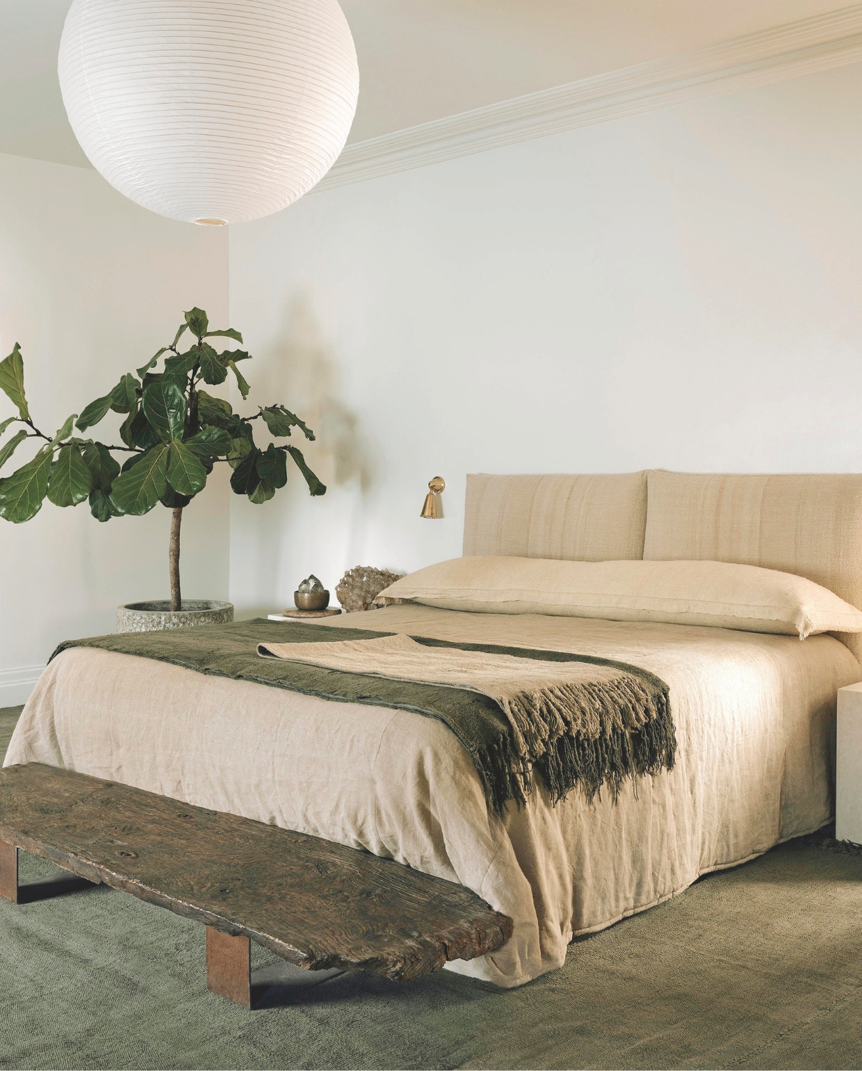 Op het bed vintage linnengoed en handgeweven Turkse vlastapijten. Hoofdeinde is bekleed met een oude sprei. De karpetten zijn tweedehands en door Anna geverfd. Bollamp Hay. Nachtlamp Rose Uniacke. vtwonen Landelijk 01-2026 | styling Ali Heath | fotografie Michael Sinclair