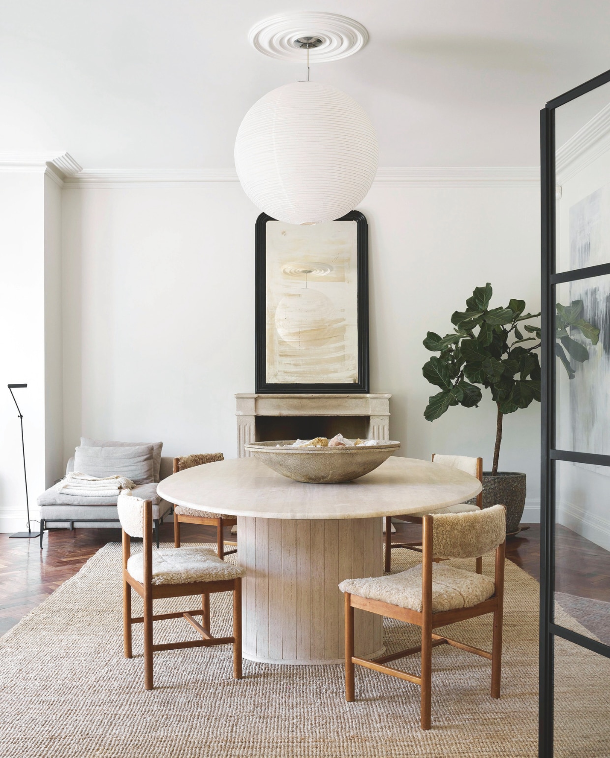 Gerecyclede visgraatparketvloer uit een voormalig MI5-kantoor in Londen. Antieke stenen schouw en verweerde antieke spiegel uit Frankrijk. Seventies travertin eettafel. Rijstpapieren bollamp Hay. Vergelijkbaar juten vloerkleed Het Jagershuis. vtwonen Landelijk 01-2026 | styling Ali Heath | fotografie Michael Sinclair