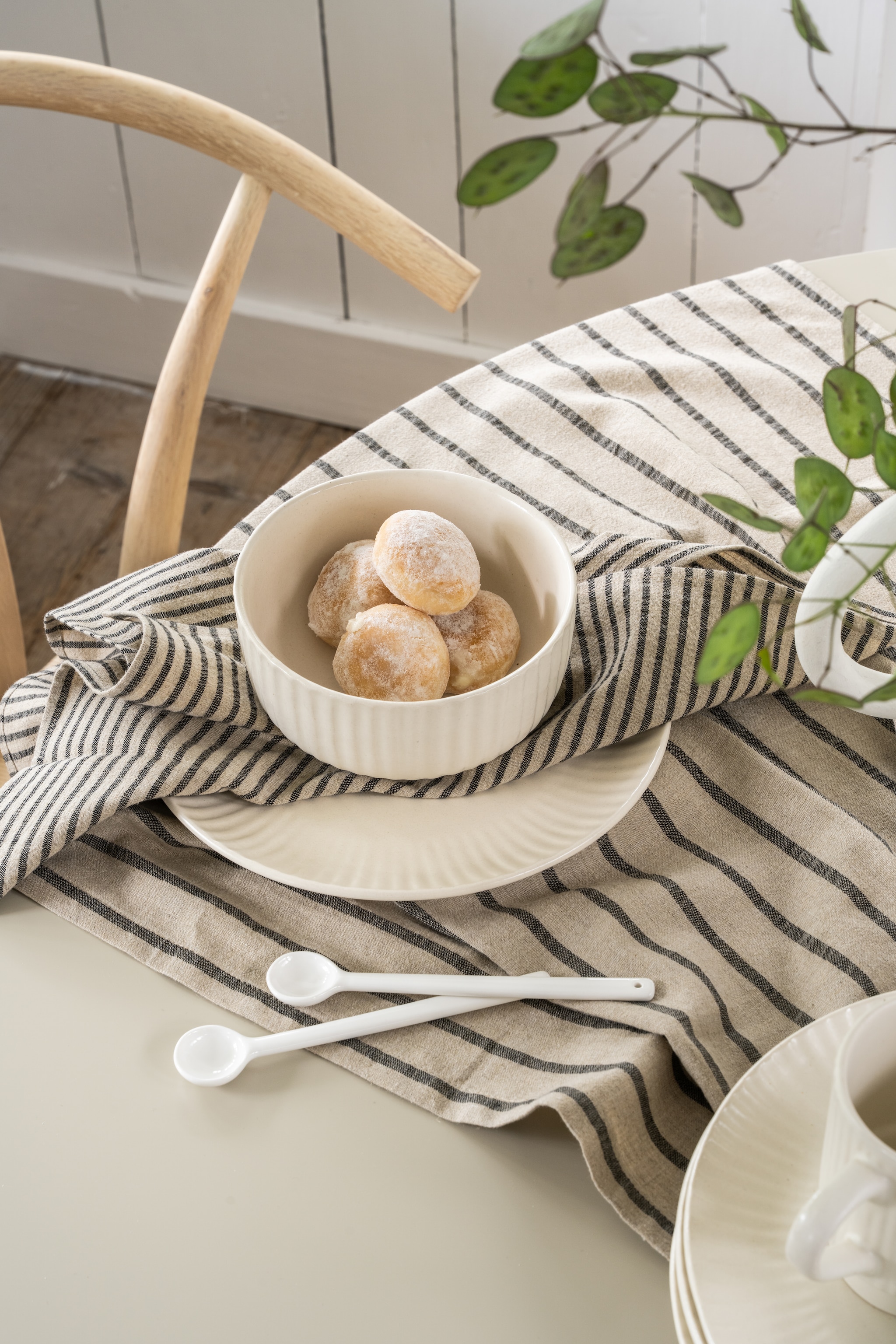 Nieuwe collectie: vtwonen lepels wit, porselein, diverse formaten, set van 6, vanaf € 19,95, vtwonen bord, keramiek, gebroken wit, 24 cm (Ø), set van 2 € 34,95, vtwonen kom, keramiek, gebroken wit, 15 cm (Ø), set van 2 € 29,95, vtwonen tafelkleed, katoen en linnen, blauw en wit, 250x150 cm (lxb) € 79,95, vtwonen servetten, katoen en linnen, blauw en wit 40x40 cm (lxb), set van 2 € 15,95.M.m.v. fonq.nl (eetkamerstoelen Okke). vtwonen Landelijk 04-2026 | styling Sanne Ketelaar | fotografie Stan Koolen