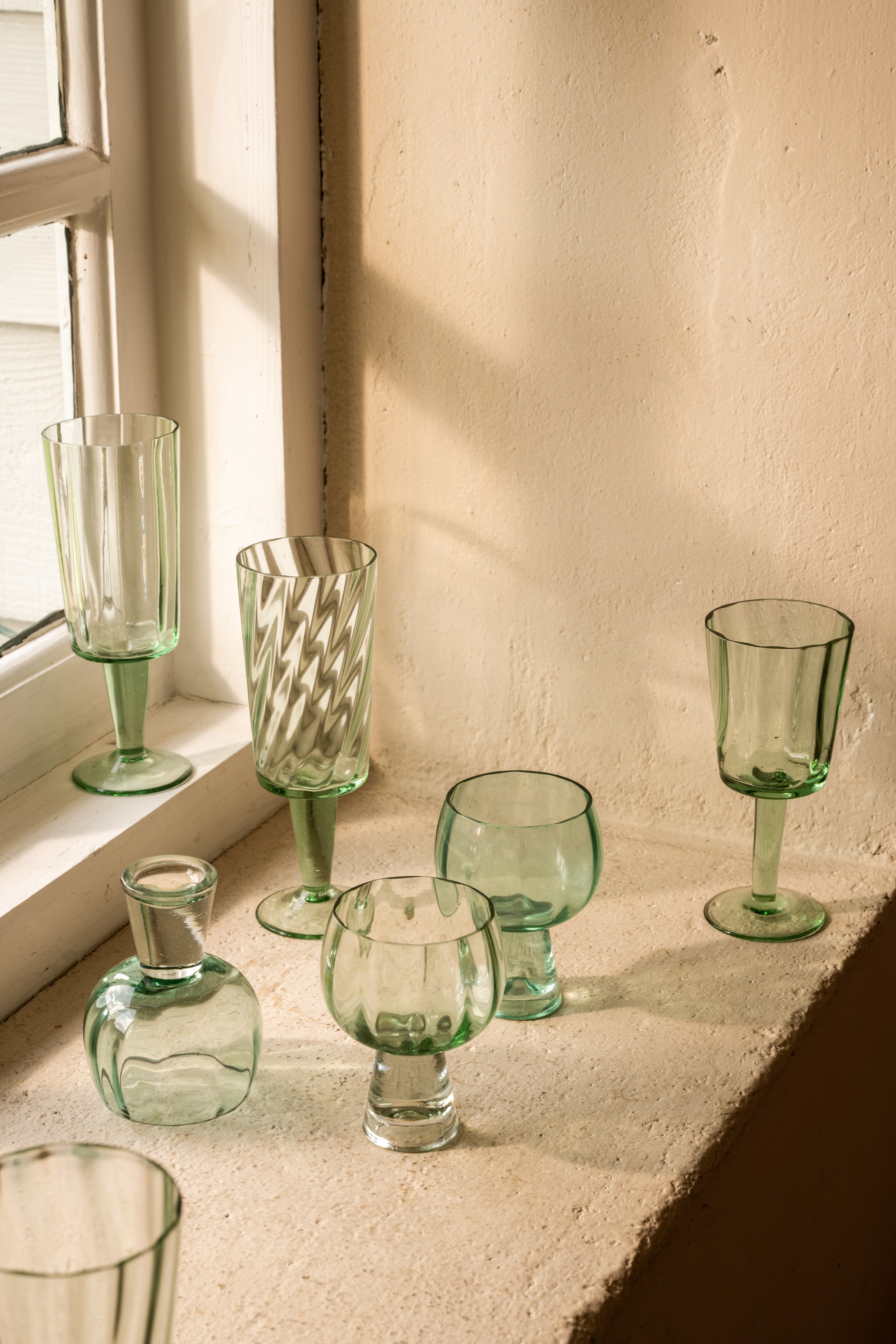 Nieuwe collectie: vtwonen champagneglas, gerecycled glas, groen, 220 ml, set van 4 € 45,-, vtwonen hoog wijnglas, gerecycled glas, groen, 270 ml, set van  € 25,90, vtwonen laag wijnglas Retro, gerecycled glas, groen, 270 ml, set van 4 € 49,-. M.m.v. fonq.nl (eettafel Marbella, stoelen Okke). vtwonen Landelijk 04-2026 | Styling Sanne Ketelaar | Fotografie Stan Koolen