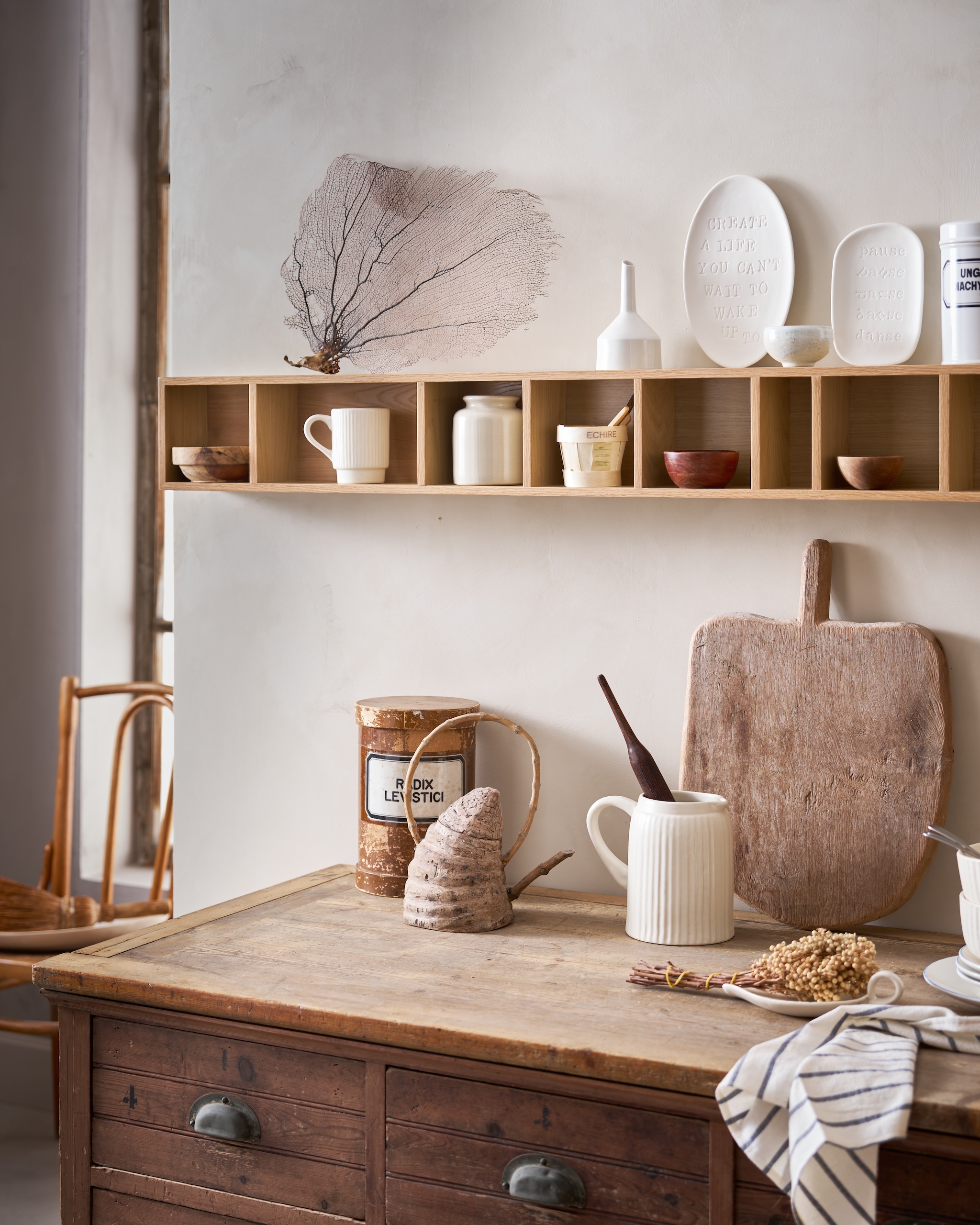 vtwonen wandkast Show It, mdf met fineer, naturel, 130x16x12 cm (lxbxd) € 89,95 (shop.vtwonen.nl).M.m.v. burbriantiek.nl (ladekast), shop.vtwonen.nl (mokken, kommen, kan, borden, schalen en servet van vtwonen). Overig privébezit. vtwonen Landelijk 04-2026 | styling Cleo Scheulderman | fotografie Jeroen van der Spek