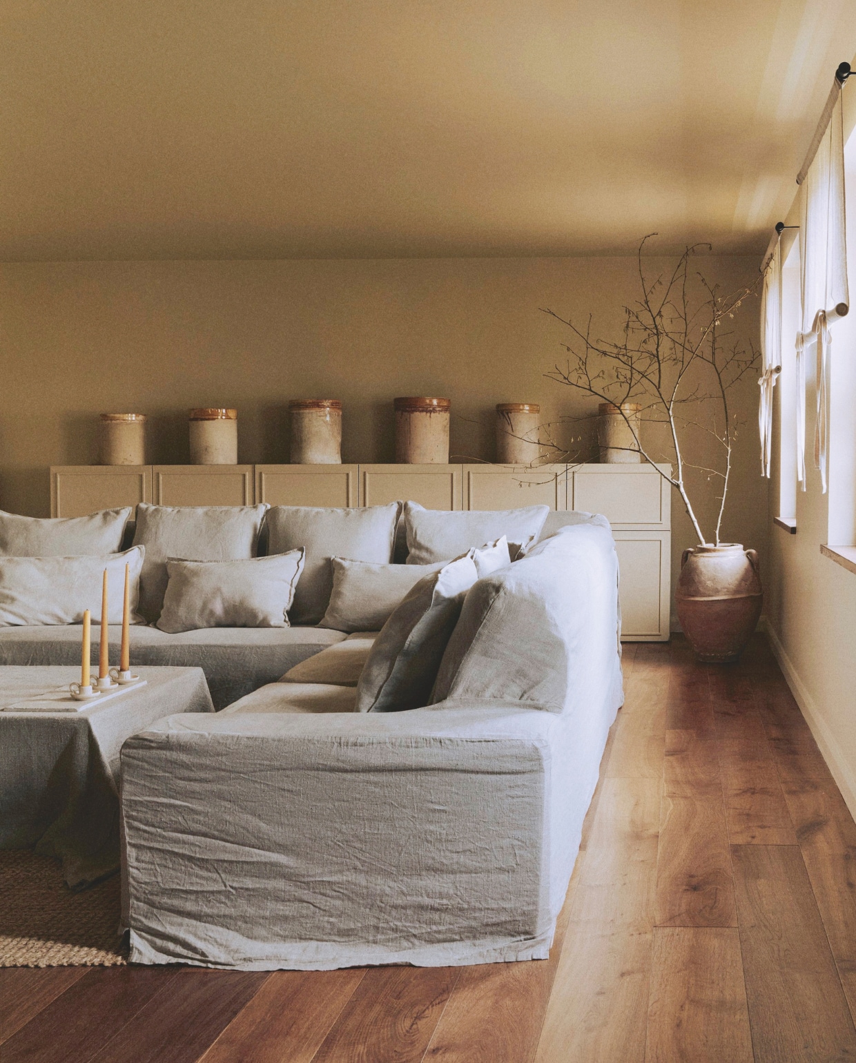 Bank met linnen bekleding Ikea. Kandelaars Zara Home. Sisal vloerkleed Alternative Flooring. vtwonen Landelijk 01-2026 | styling Ali Heath | fotografie Michael Sinclair