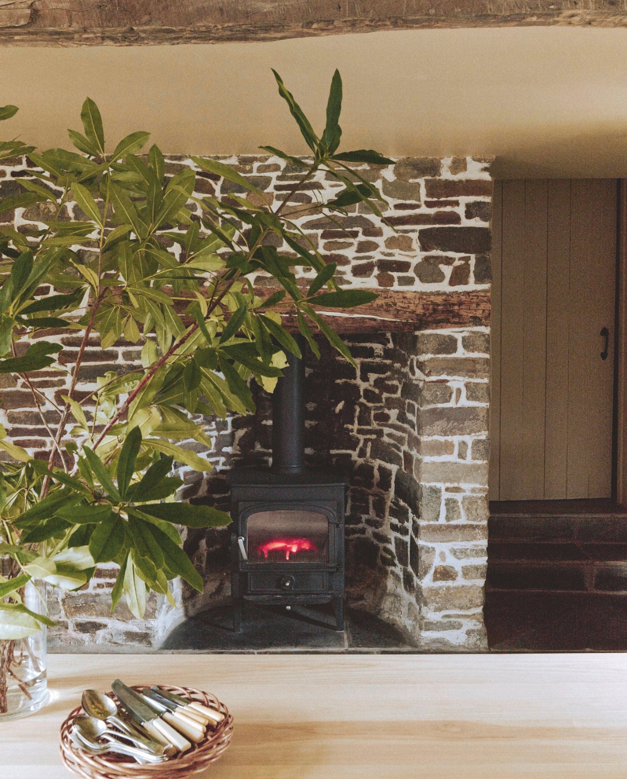 De schouw zat al in het huis en is vermoedelijk 200 jaar oud. Soort-gelijke houtkachel ’t Stokertje. Het antieke bestek is afkomstig uit een familie-erfenis. vtwonen Landelijk 01-2026 | styling Ali Heath | fotografie Michael Sinclair