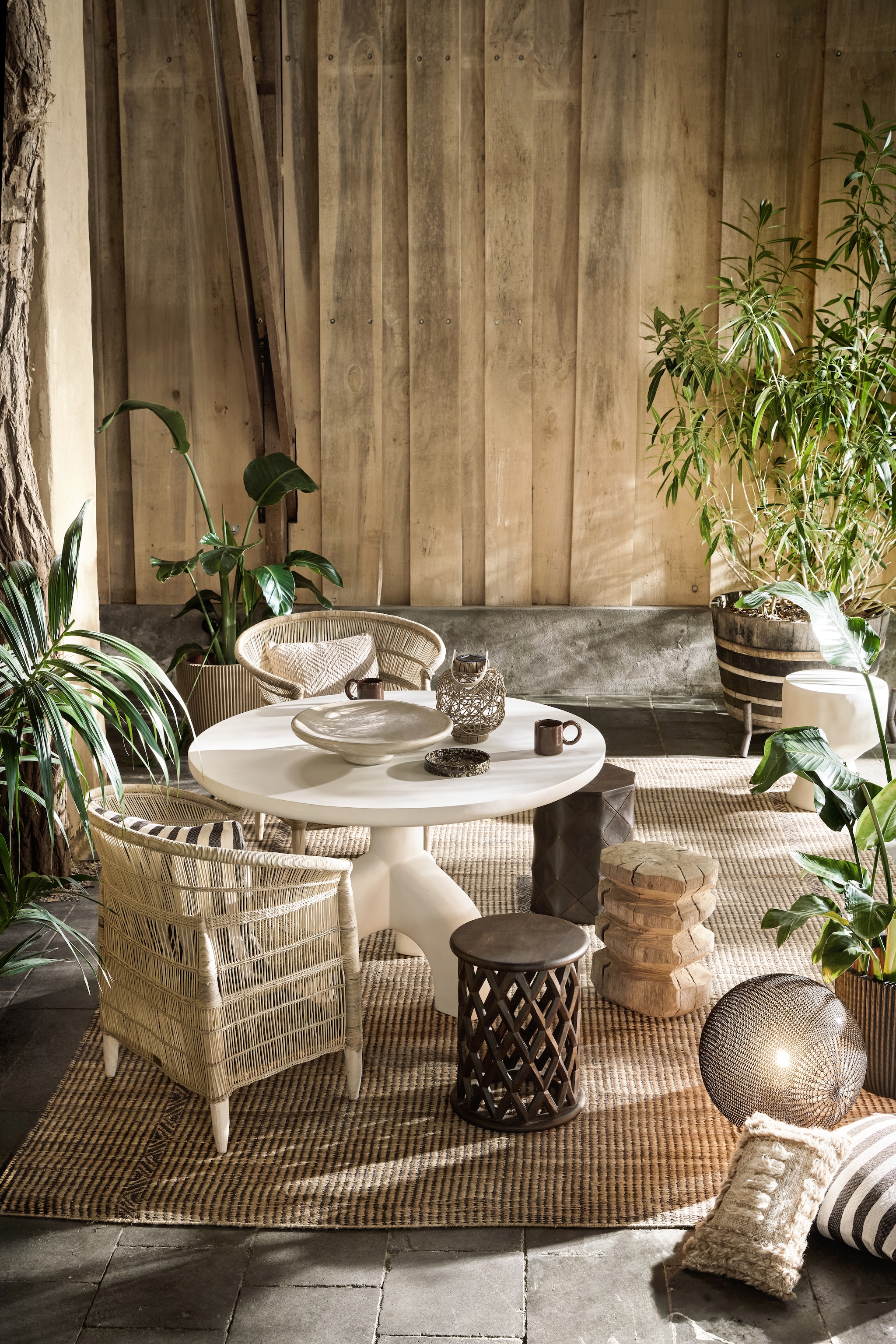 HKliving vloerkleed Desert, jute en katoen, 240x150 cm (lxb) € 379,-, kussen Furry, wol, 40x25 cm (lxb) € 44,95 (hkliving.com). Woood eettafel Luno, vezelversterkte polymeer, naturel, 120 cm (Ø) € 1099,-, witte kruk Aur, vezelversterkte polymeer, naturel € 299,- (woood.nl). Mala Africa stoelen Mala Klassieker, handgemaakt in Malawi, waterriet, hout en bamboe, per stuk € 269,- (malaafrica.com). Raw Materials kruk Pacific Palau met opengewerkt ruitmotief, mangohout € 255,-, kruk Pacific Tonga met dicht ruitmotief, mangohout € 275,- (rawmaterials.eu). Tribù buitenlamp Monsieur Tricot,  Madame Latoque, gehaakte hoes, draadloos, lebonnet wenge € 1070,-(dacks.nl). Capi Europe pot Groove met ribbels, taupe € 139,-, zwart€ 49,99 (intratuin.nl). Household Hardware schaal, tadelakt € 159,-, gestreepte kussens, bruin/wit€ 69,95, mok met groot oor, bruin€ 15,95, bord Spongeware, bruin€ 25,- (householdhardware.nl). vtwonen special 01-2026 | Styling Marlies Does | fotografie Peggy Janssen