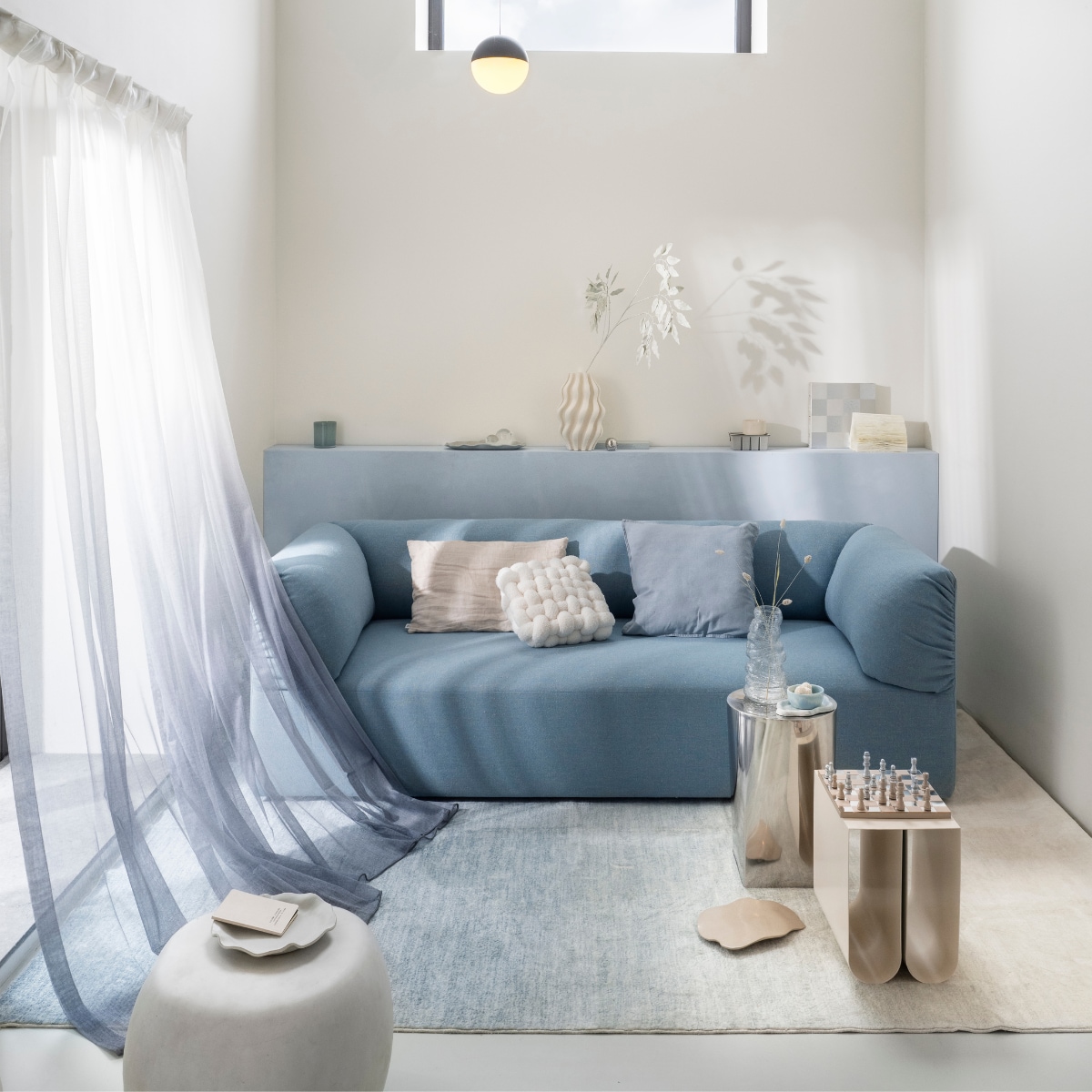 Studio henk driezitsbank Unfold, stof hemp, Dale HWP18, 220x90x70 cm (bxdxh) € 4000,- (studiohenk.nl). Printworks schaakbord Classic art of chess, hout en spiegelglas, zilverkleurig € 125,-, vtwonen bijzettafel Pebble, betonlook, wit, 35x50 cm (Øxh) € 199,-, HKliving schaaltje Patio, pale blue € 16,95,- (shop.vtwonen.nl). H&m home kussenhoes, linnenmix, dusty blauw € 9,99, klein bord met geschulpte rand, terracotta, wit, (Ø) 20 cm € 14,99 (hm.com). Zara home bijzettafel, roestvrij staal, zilver, 30x46 cm (Øxh) € 159,-, rond kistje, metaal, zilver € 6,99, kaars, decoratief keramiek, wit € 15,99 (zarahome.com). Kristina Dam bijzettafel Curved, metaal, beige, 26x35,5x36 cm (bxdxh) € 279,- (kristinadam.dk). Trend carpet gordijn Linda royal, polyester, wit/blauw, 140x260 cm (bxh) € 39,99 (trendcarpet.nl). By mölle kussenhoes, linnen, clay € 59,- (bymolle.com). Karwei vaas, keramiek, wit, 3D-geprint, vtwonen muurverf op de lambrisering, kleur Ice, 1 liter € 27,99,- (karwei.nl). Kwantum vaas Cagnola, glas, transparant € 7,-, kussen Knit, polyester, wit € 25,- (kwantum.nl). Idimex vloerkleed Ombre, wasbaar polyester, lichtblauw met kleurverloop, 200x300 cm (lxb) € 129,- (idimex.de). Ikea kaarshouder Vindstilla, aardewerk, licht grijsgroen € 5,09 (ikea.nl). Stonecloud dienblad, aardewerk, beige, prijs op aanvraag (stonecloudbynika.com). Overig privébezit. vtwonen 01-2026 | styling Sanne Ketelaar | fotografie Stan Koolen
