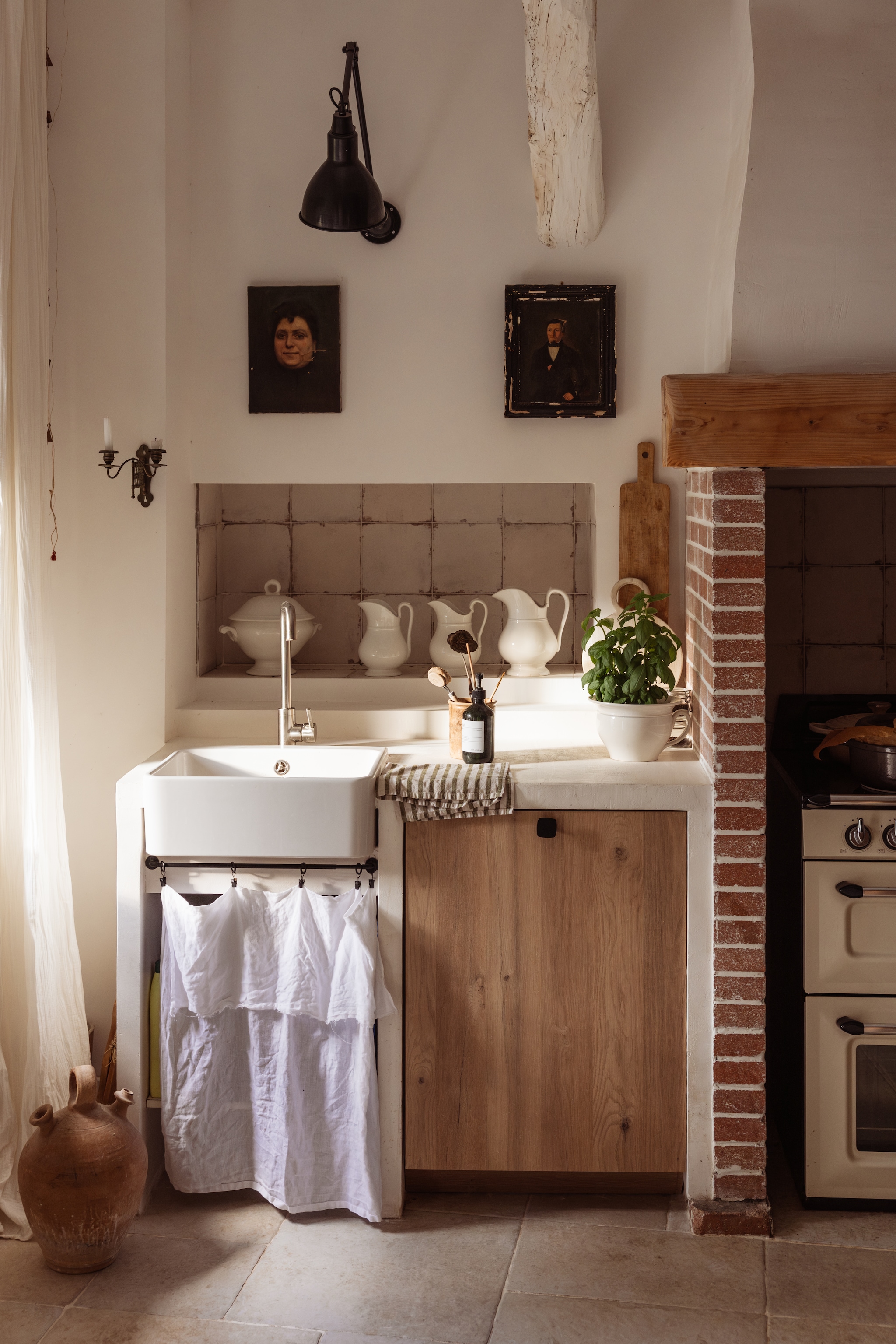 Keukenblok en linnen gordijnzelfgemaakt. Kannen, schilderijen, houten broodplank, kruik en wandlamp brocante. Theedoek Le French Finds. vtwonen Landelijk 04-2026 | Fotografie Dana van Leeuwen | Styling Ilona Jongepier