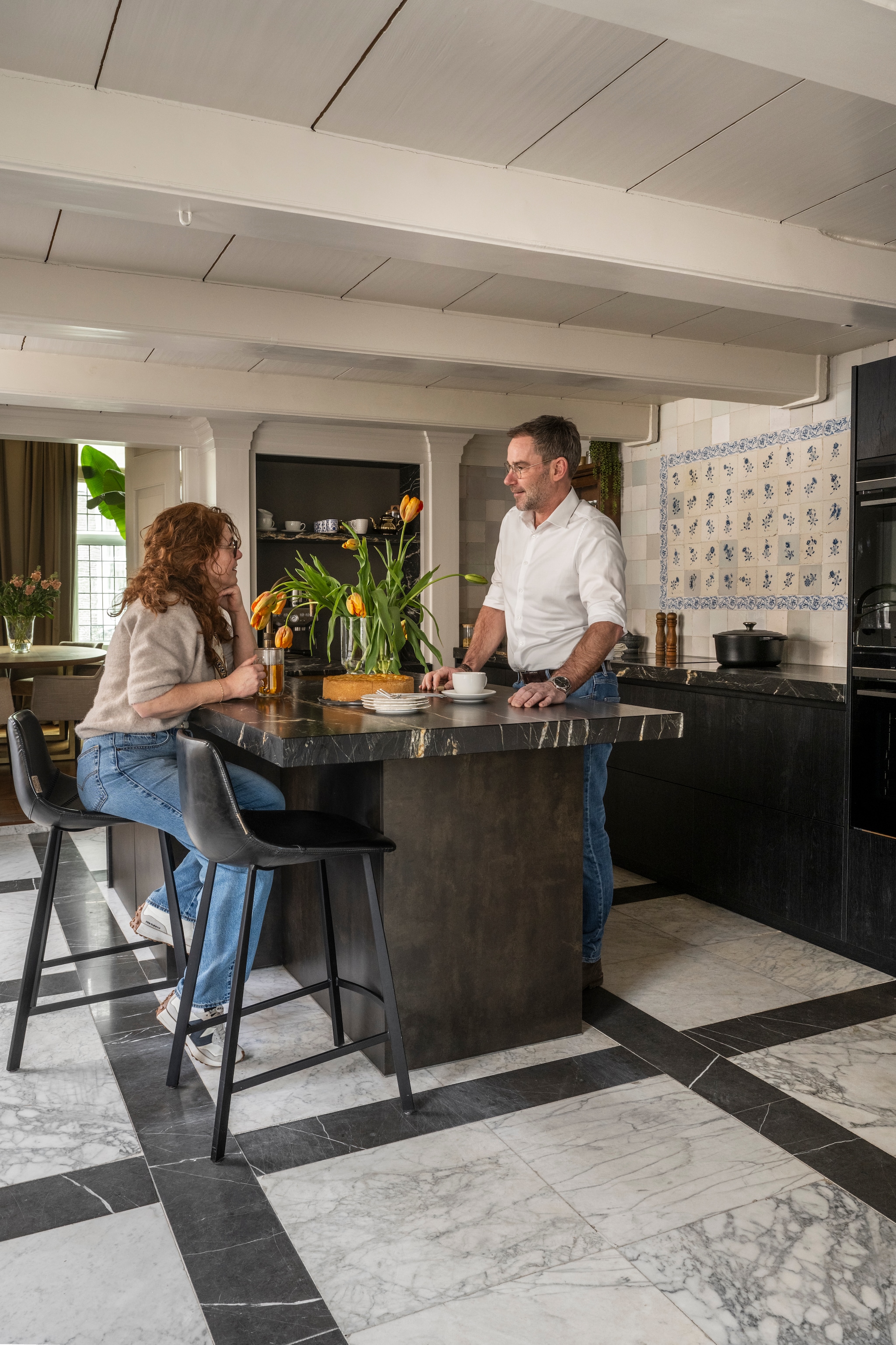 Keuken eigen ontwerp, gemaakt door Mdb Interieur. Barkrukken Dutchbone. Pan Le Creuset. Grijze tegels Dapper en Harder. Muurtegels en witte marmeren vloertegels zaten al in het huis. vtwonen Landelijk 04-2026 | styling Marianne Luning | fotografie Stan Koolen