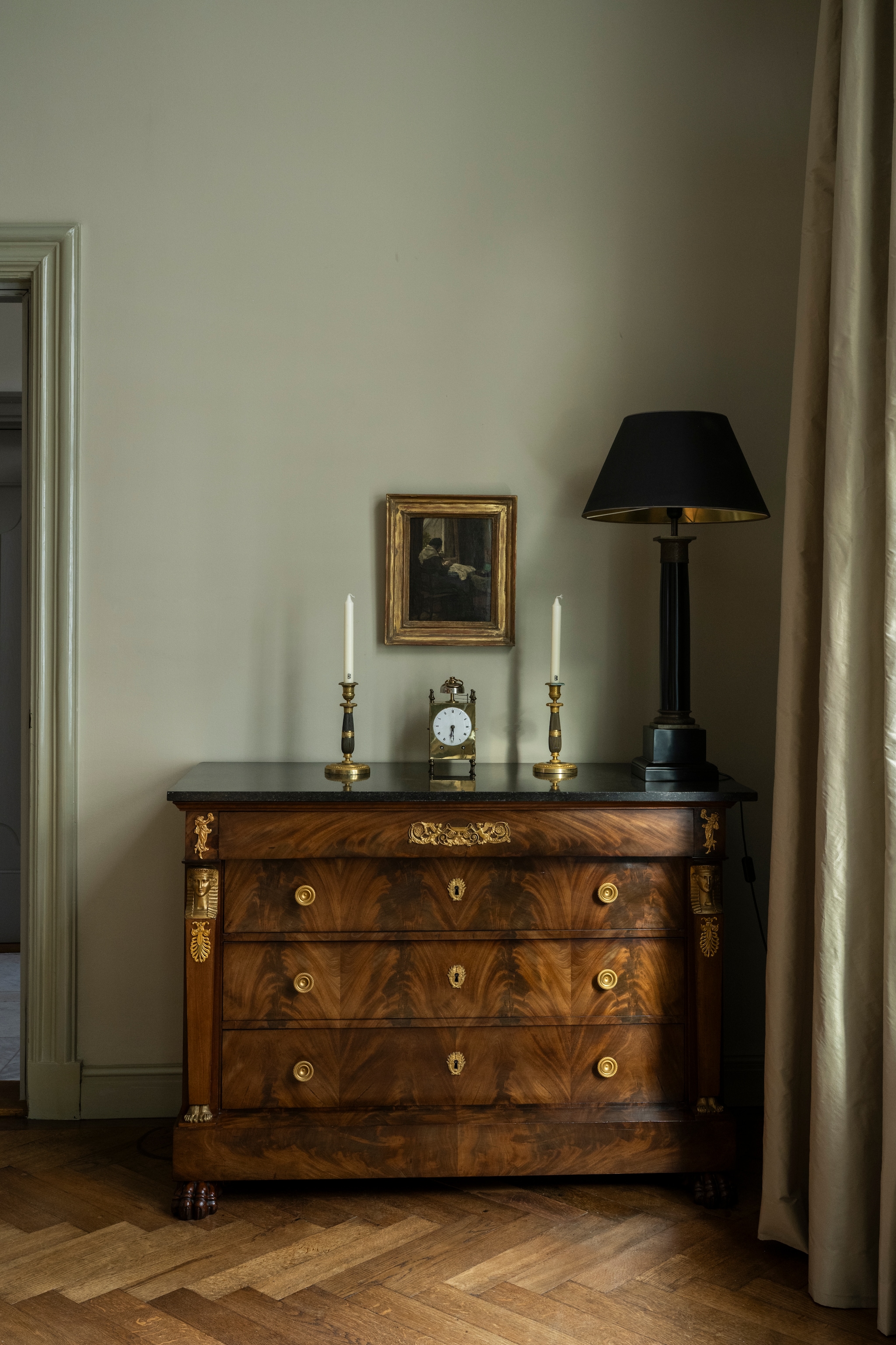Antieke commode en kandelaars Kuipers Kunst & Antiek. Lamp Decoration Empire. Schilderij en klok van een veiling. Parketvloer uit 1908 zat al in het huis. Kleur muur Bone van Farrow & Ball. vtwonen Landelijk 04-2026 | styling Marianne Luning | fotografie Stan Koolen