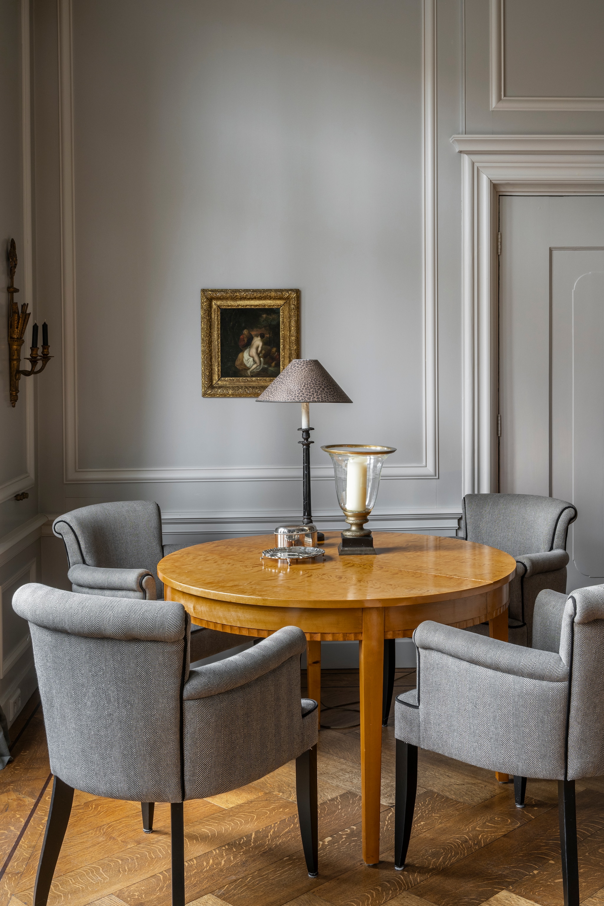 Tafel, windlicht, schilderij, kandelaar aan de muur veilinghuis. Stoelen Amelink. Vloer Leguit en Roos.Muurkleur Purbeck Stone van Farrow & Ball. vtwonen Landelijk 04-2026 | styling Marianne Luning | fotografie Stan Koolen
